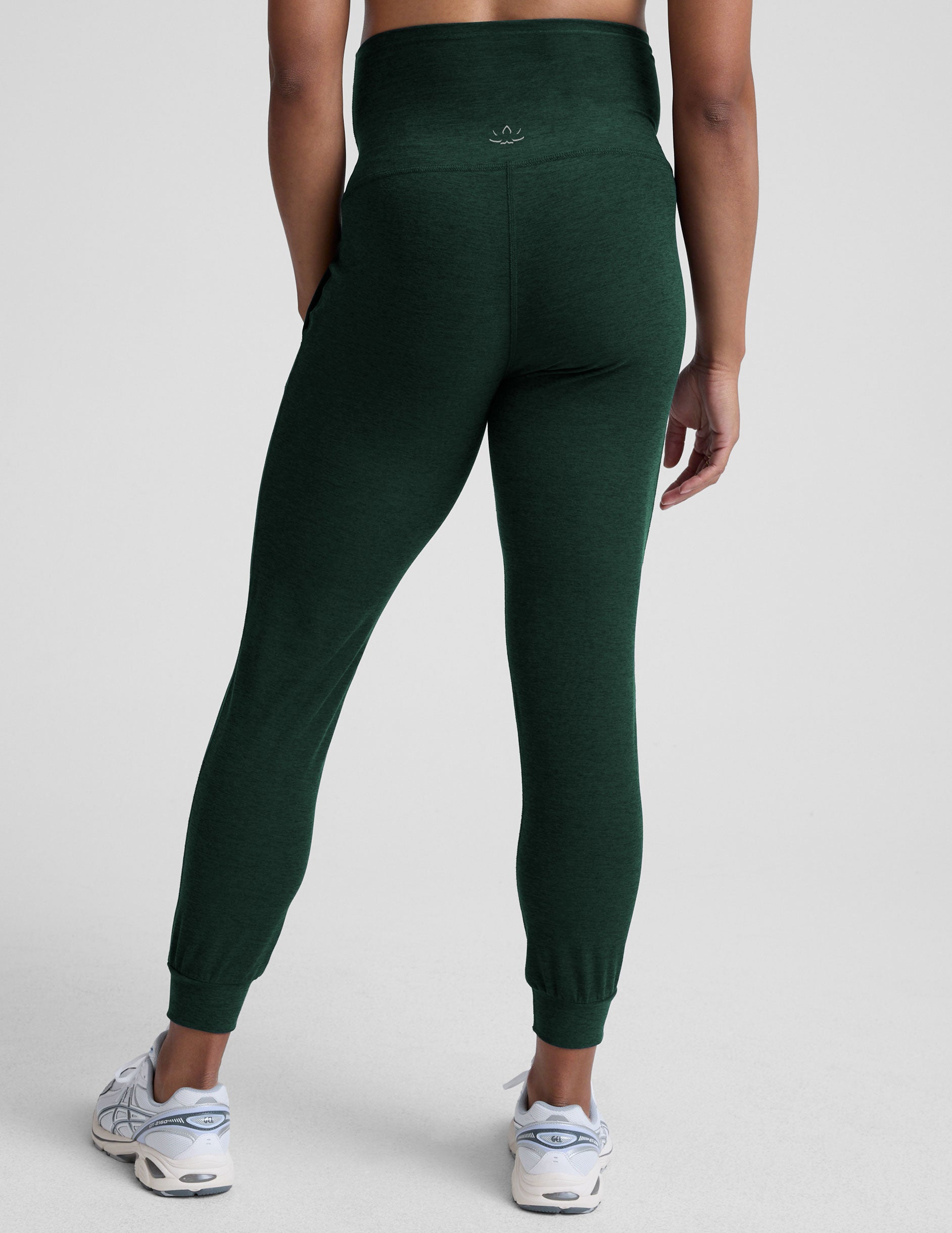 model wearing green maternity midi length joggers with pockets on a plain background.