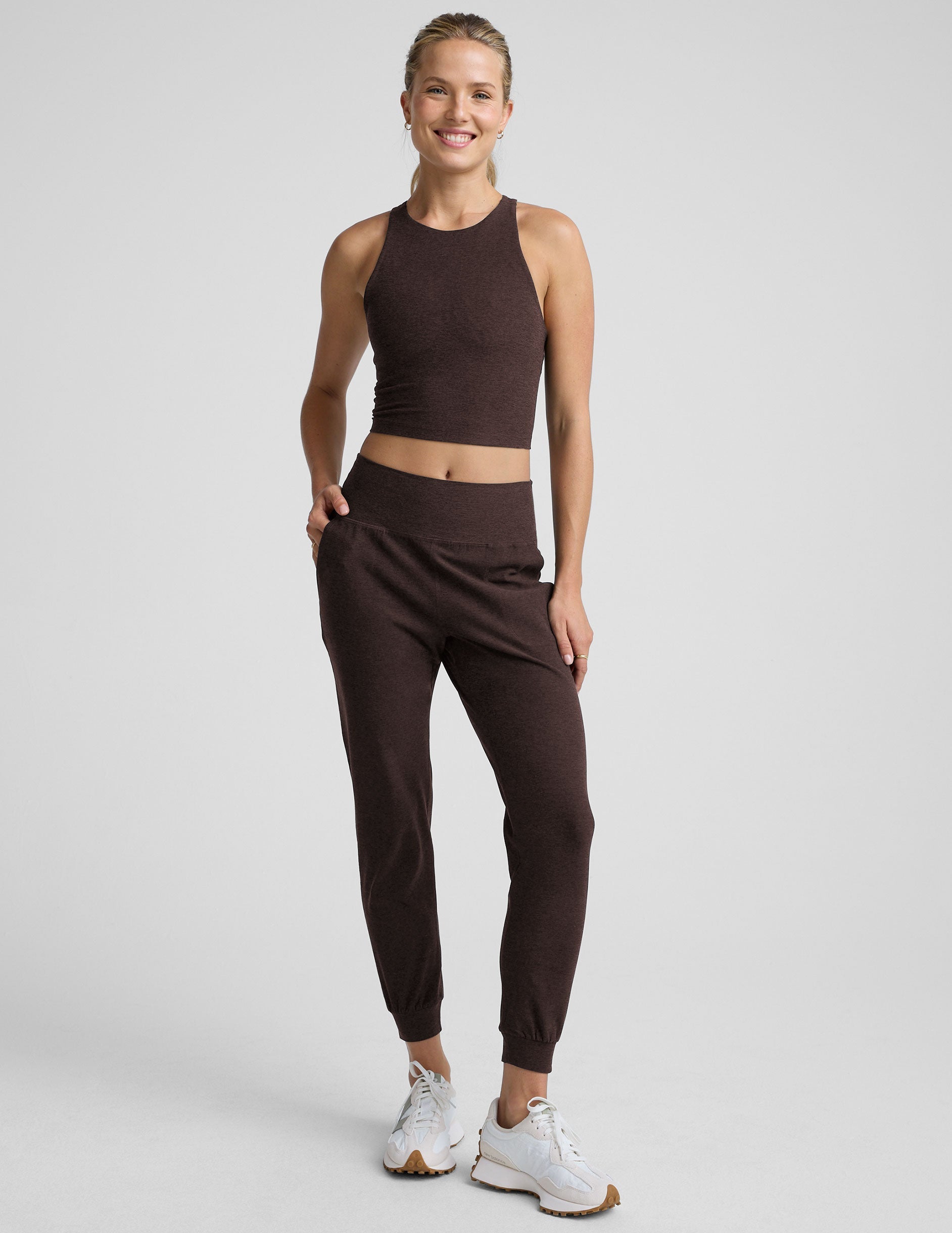 Woman wearing a chocolate brown athletic outfit on a white background