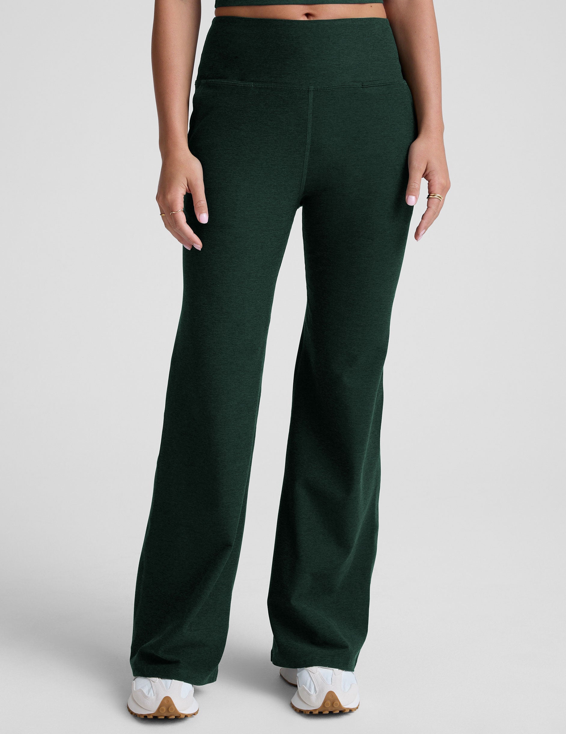 model wearing dark green high-waisted wide leg pants with pockets on a plain background.
