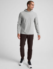 male model wearing a grey hoodie and brown men's sweatpants with zipper pockets on a plain background.