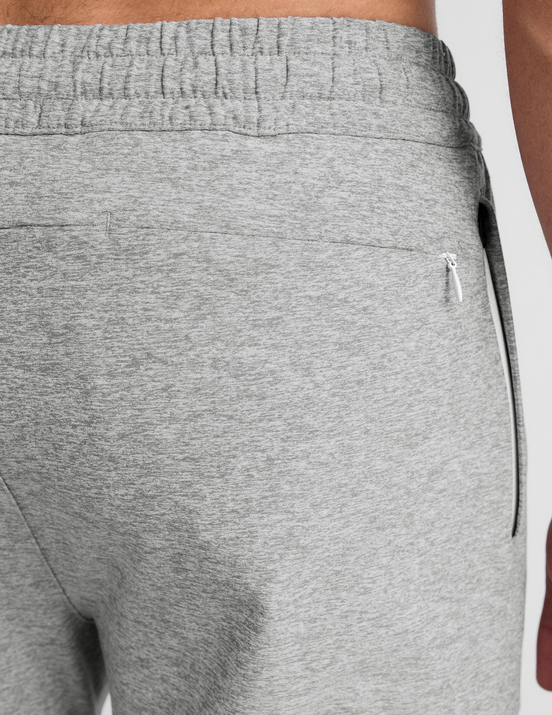 man wearing a black t-shirt and gray sweatpants on a plain background.