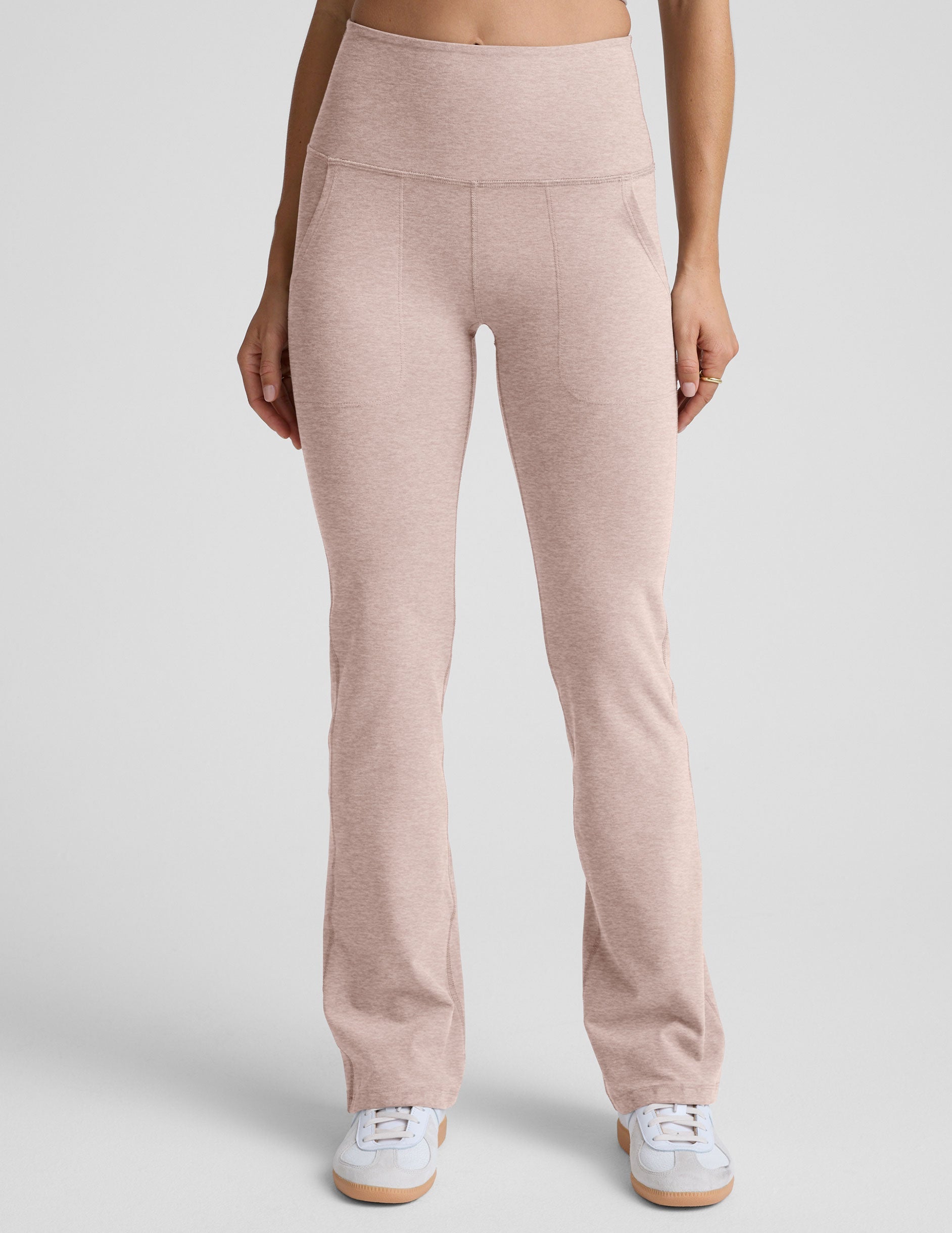 model wearing pink high-waisted bootcut pants with pockets set on a plain background.