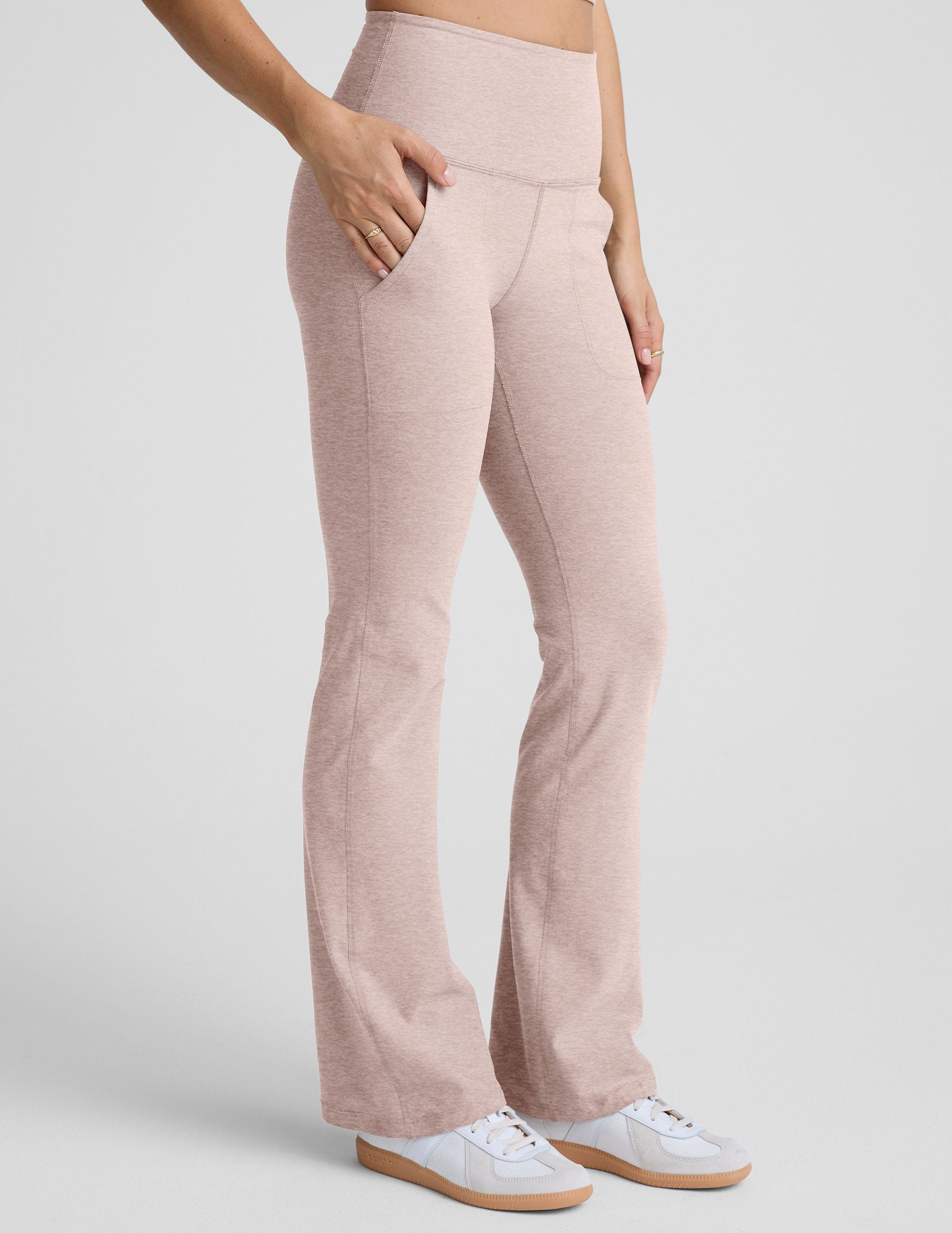 model wearing pink high-waisted bootcut pants with pockets set on a plain background.
