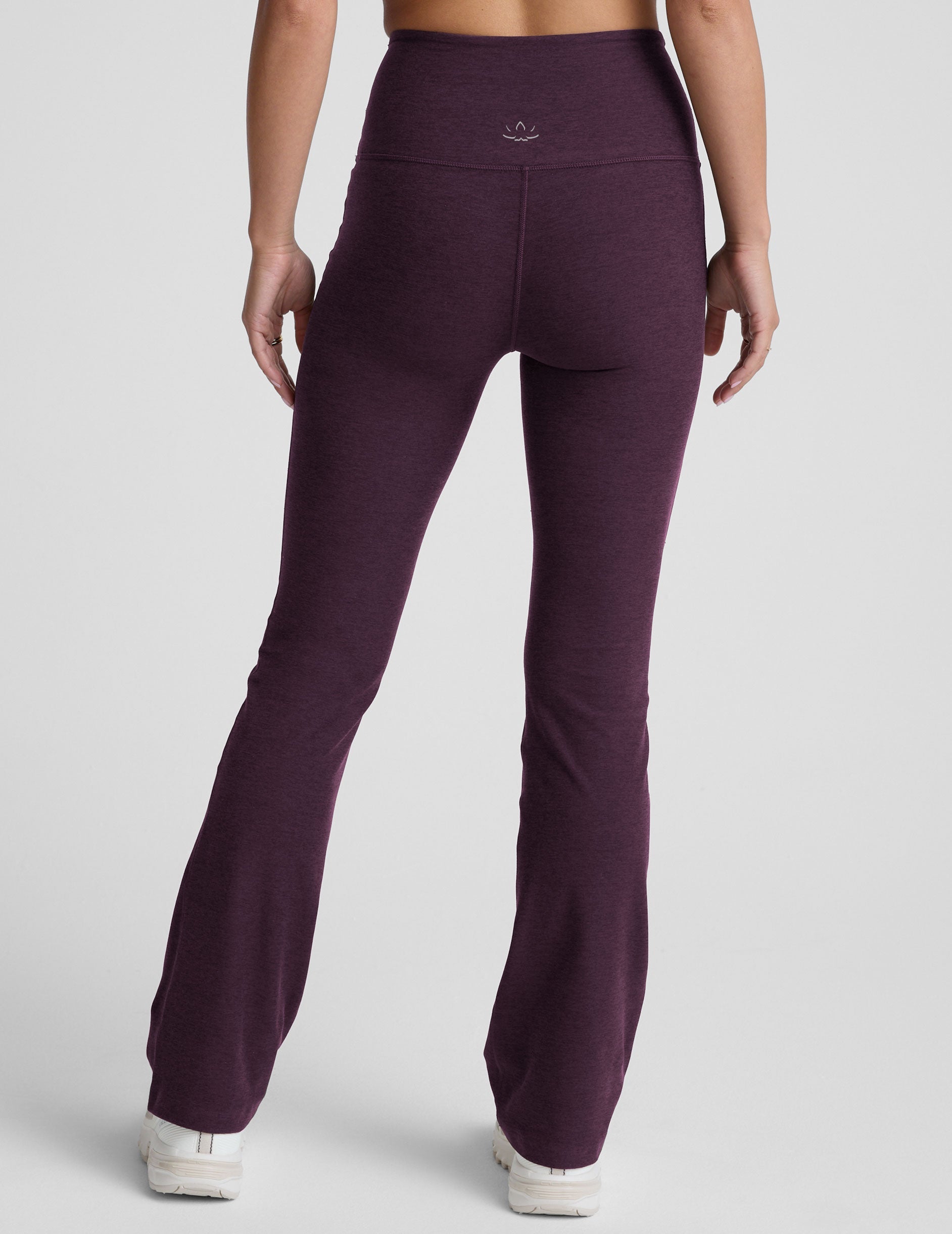 model wearing purple high-waisted bootcut pants with pockets on a plain background.