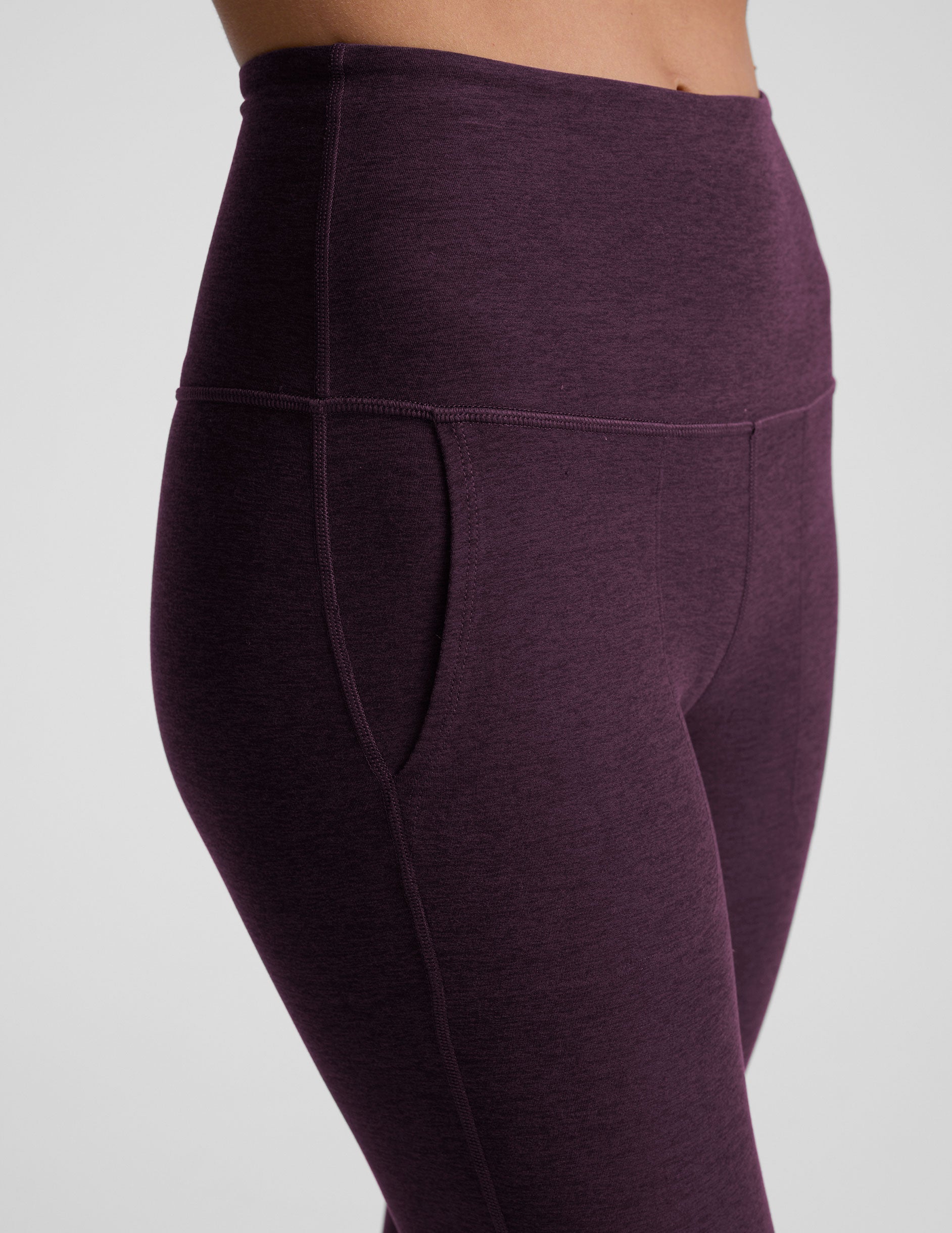 model wearing purple high-waisted bootcut pants with pockets on a plain background.