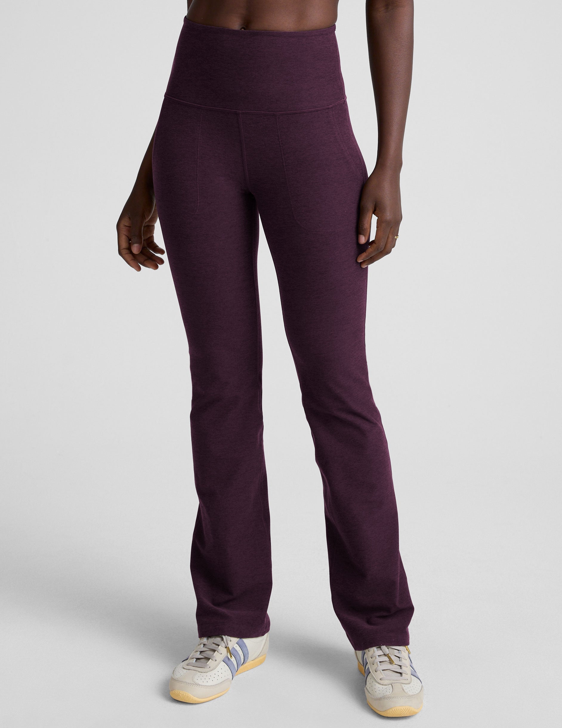 model wearing purple high-waisted bootcut pants with pockets on a plain background.