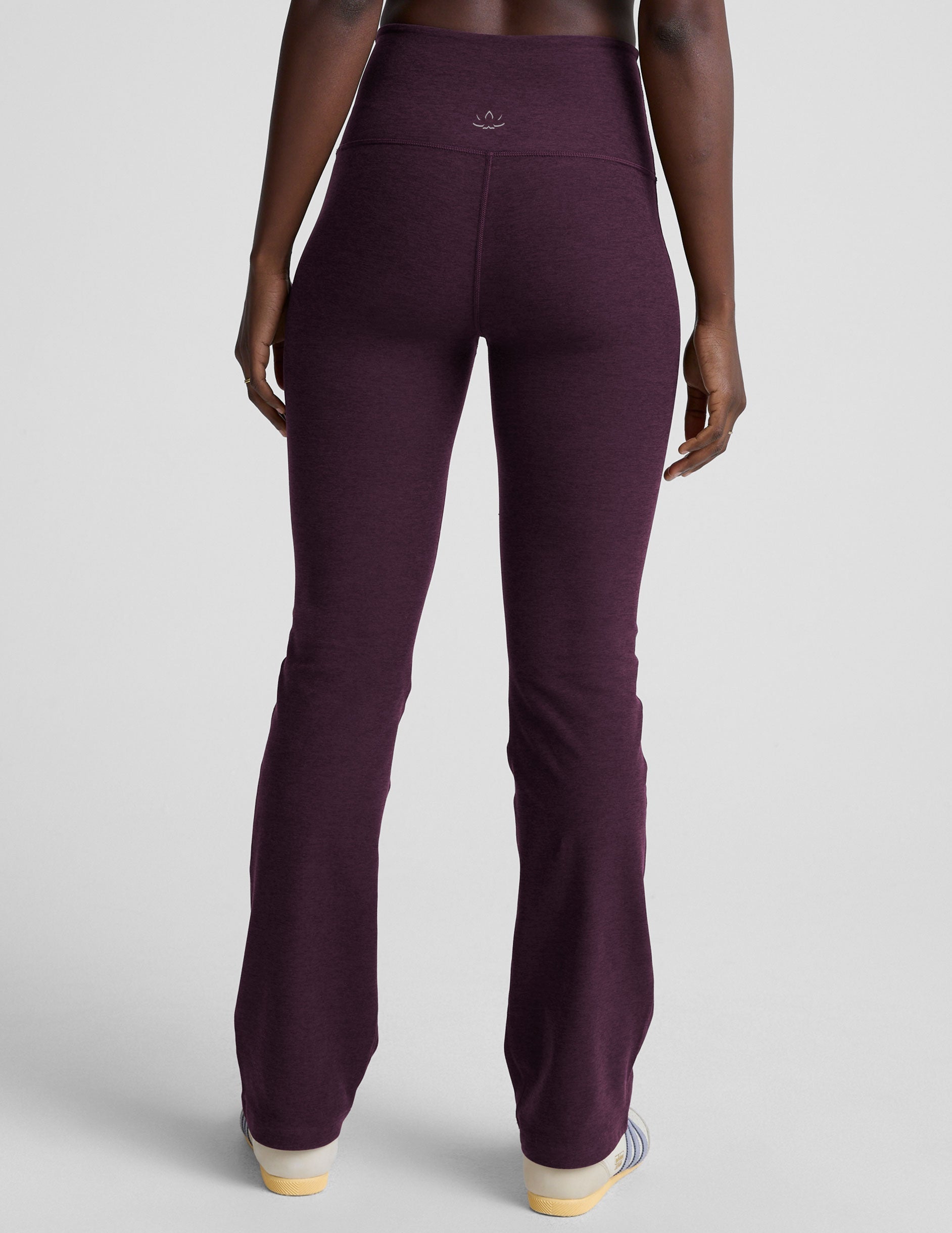 model wearing purple high-waisted bootcut pants with pockets on a plain background.