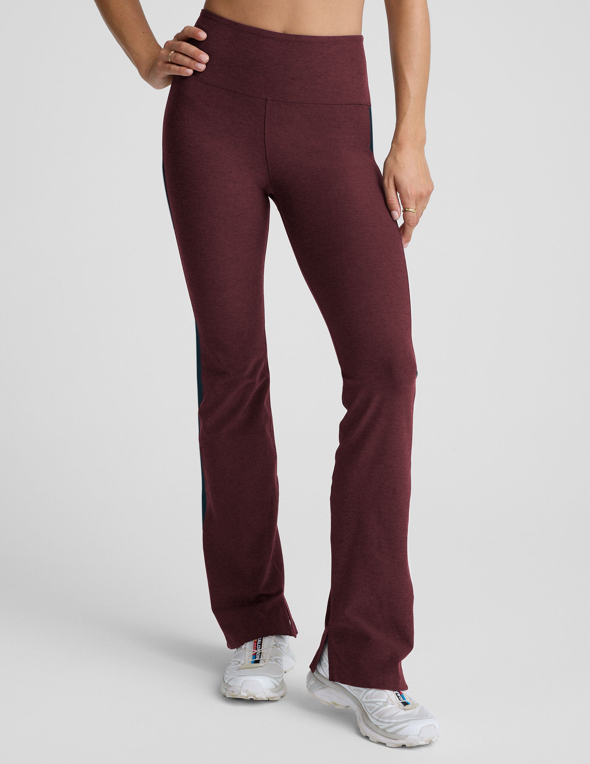 model wearing burgundy pants with a blue stripe on a light gray background.