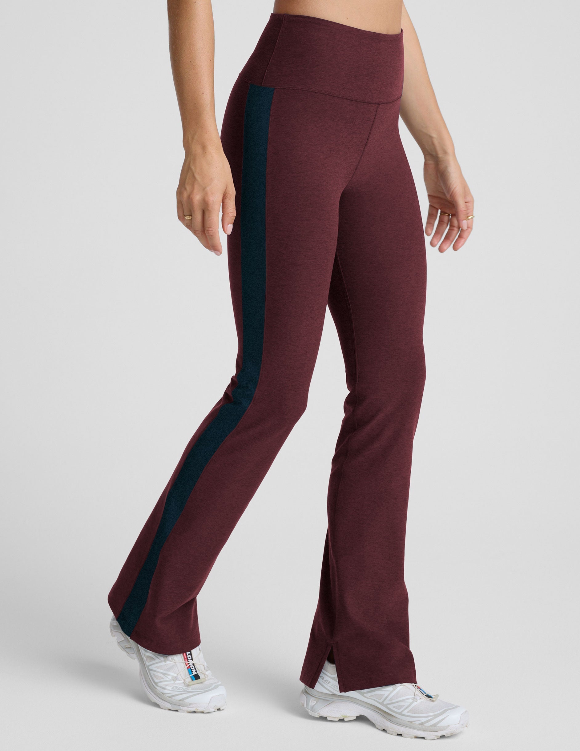 model wearing burgundy pants with a blue stripe on a light gray background.
