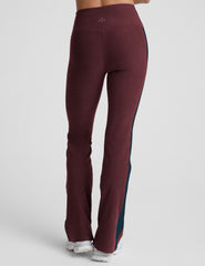 model wearing burgundy pants with a blue stripe on a light gray background.