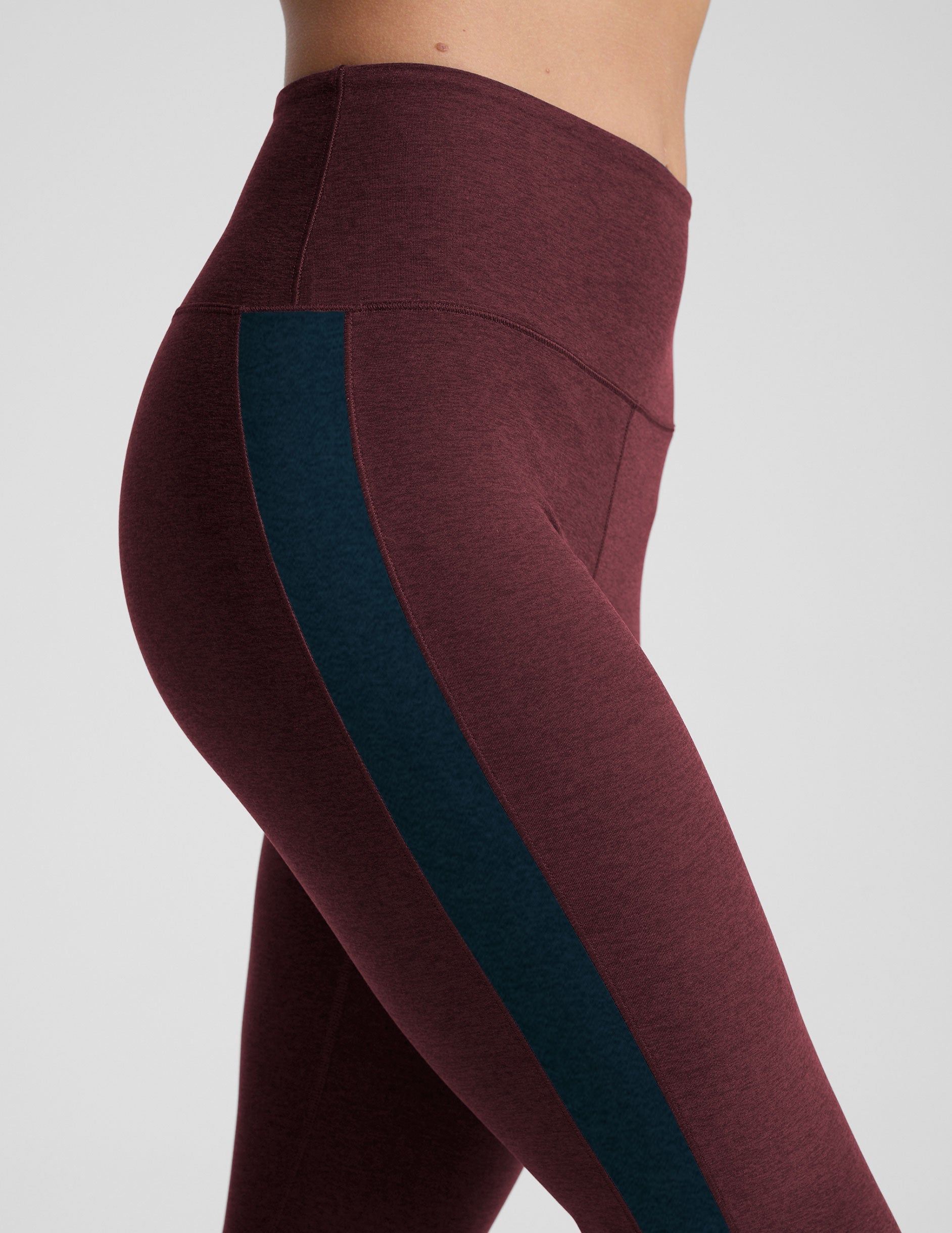 model wearing burgundy pants with a blue stripe on a light gray background.