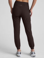 woman wearing a brown joggers with pockets on a light gray background.