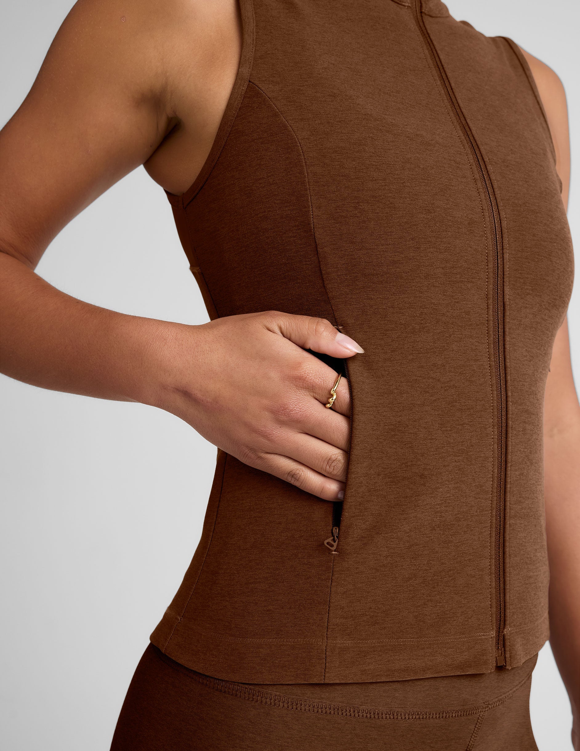 brown zip-up vest with a mesh upper back detail and pockets.