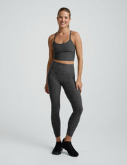 woman wearing a gray cropped tank and long length leggings on a plain background.
