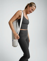 woman wearing a gray cropped tank and long length leggings on a plain background.