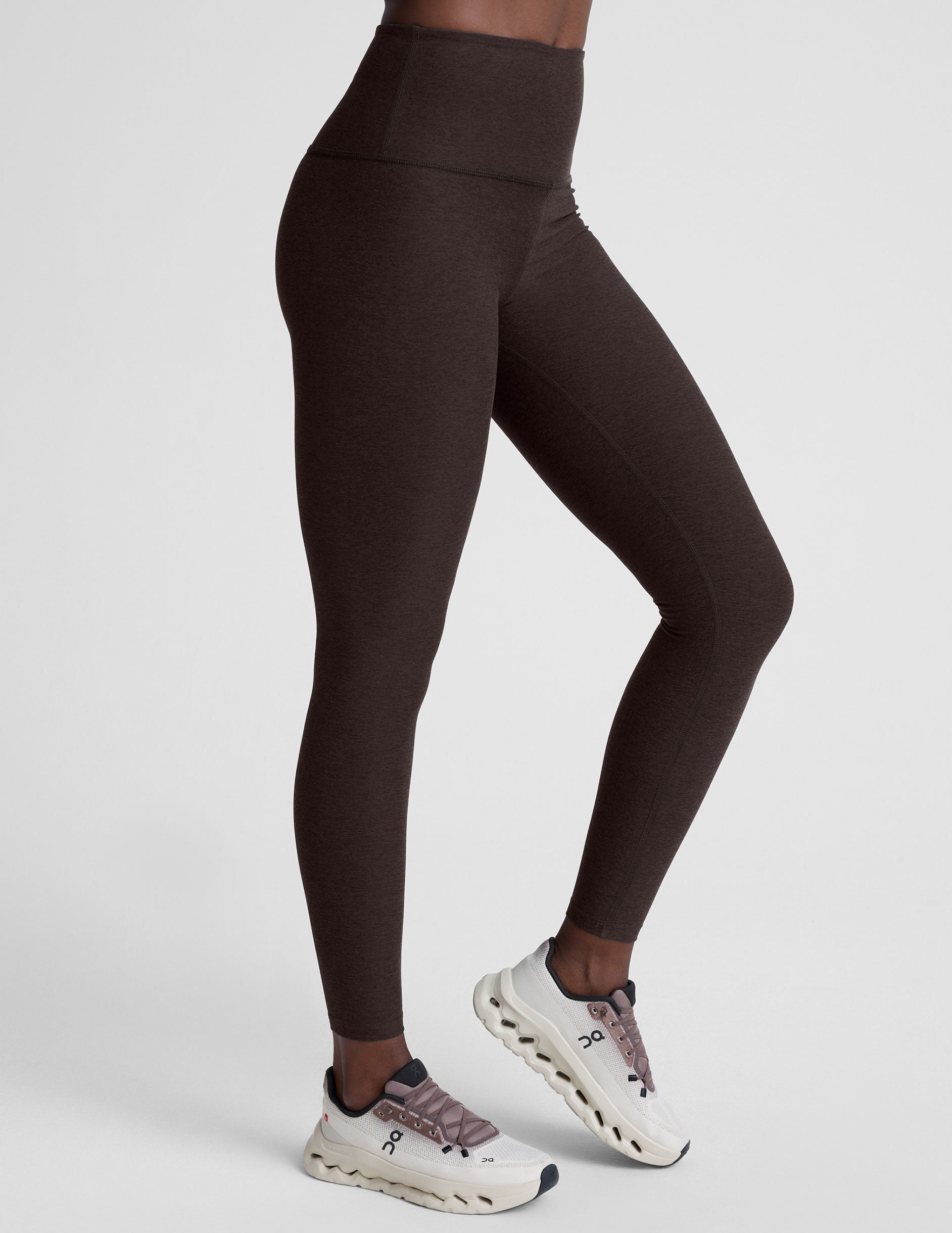 woman wearing a brown sports bra and long leggings set on a white background.