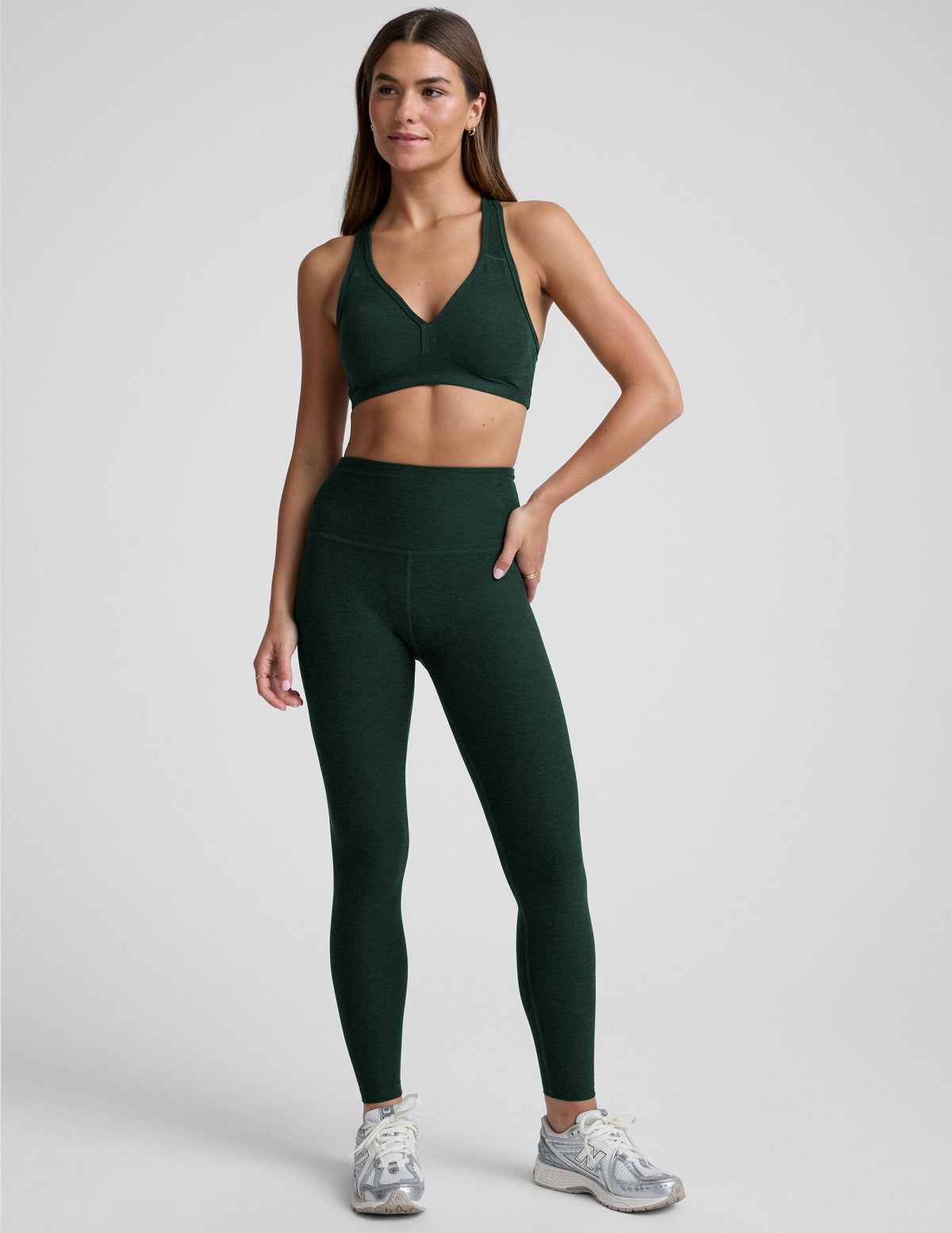 model wearing a green athletic bra and green high-waisted full length leggings on a plain background.