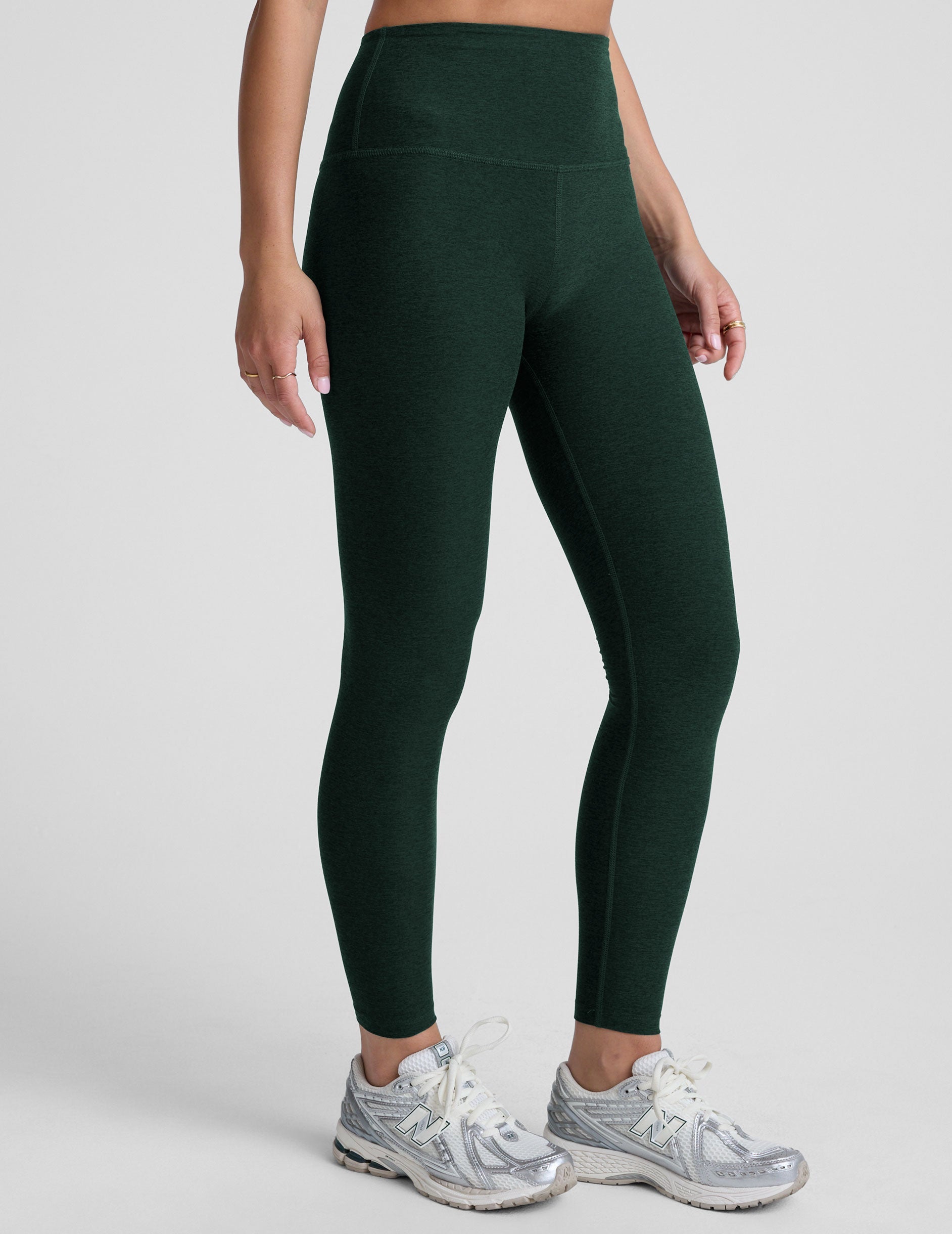 model wearing green high-waisted full length leggings on a plain background.