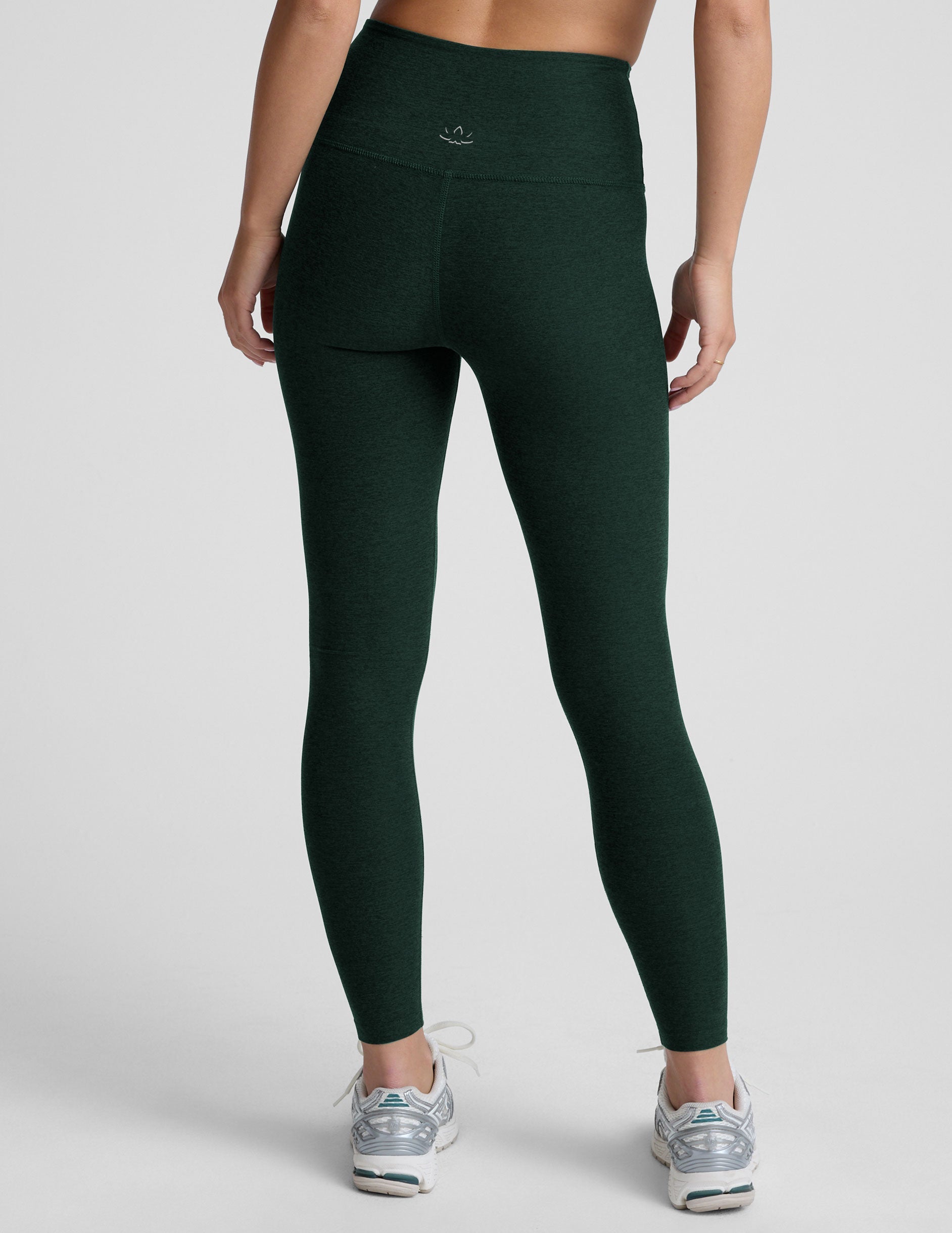 model wearing green high-waisted full length leggings on a plain background.