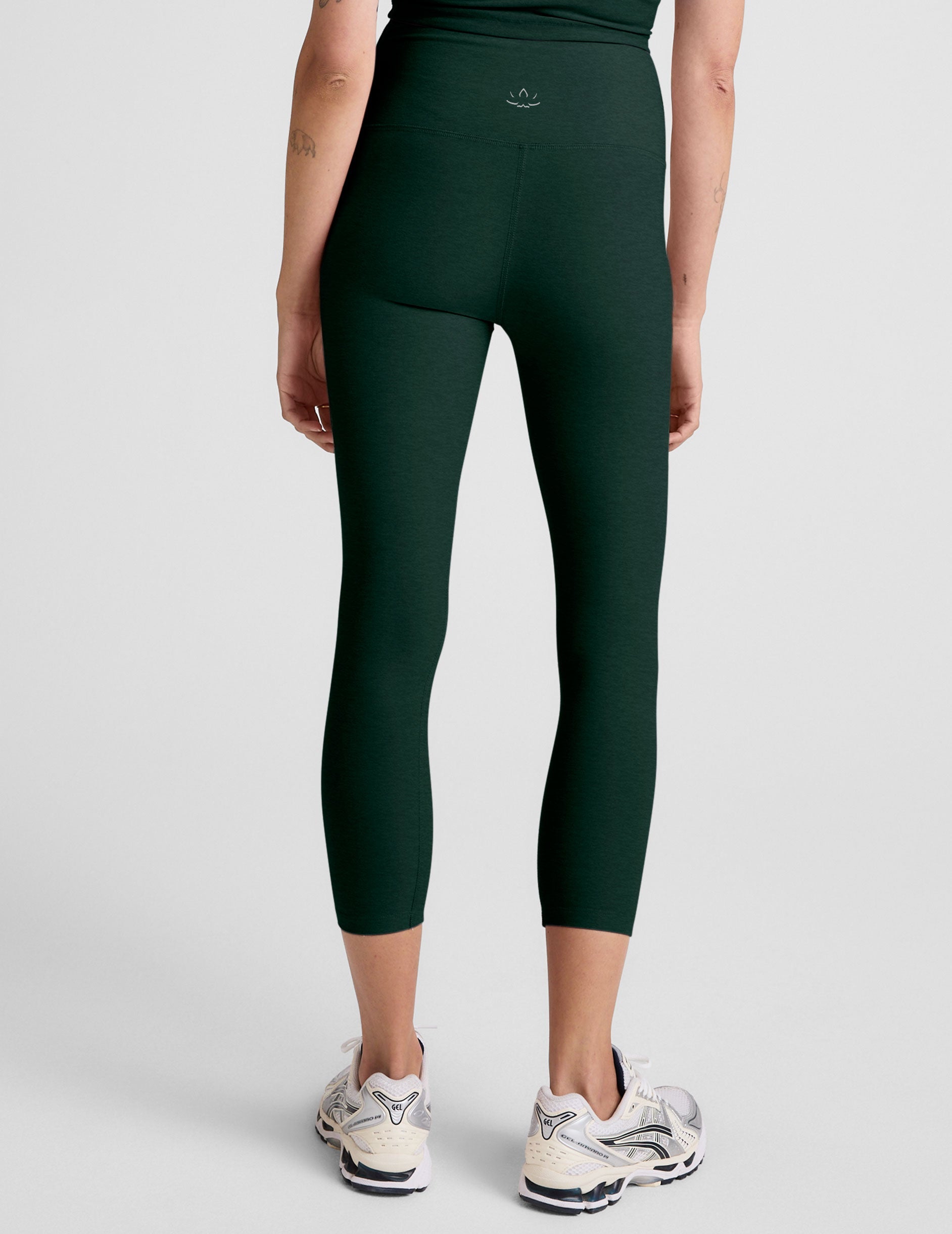 model wearing green high-waisted capri leggings on a plain background.