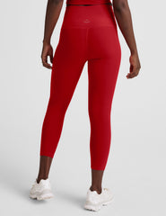 woman wearing a red cropped tank and capri length leggings on a plain background.