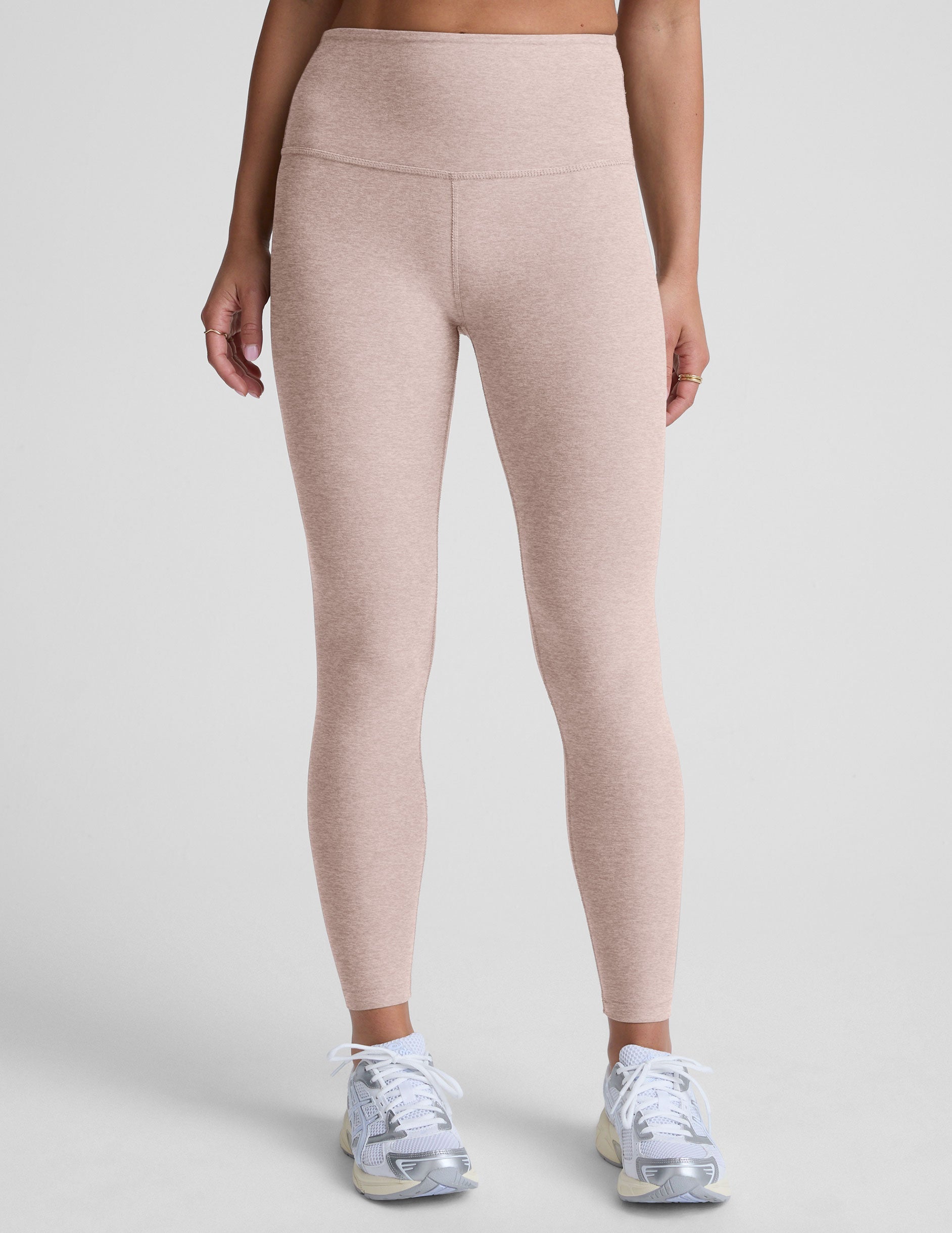 light pink high-waisted midi length leggings worn by model on a light gray background.