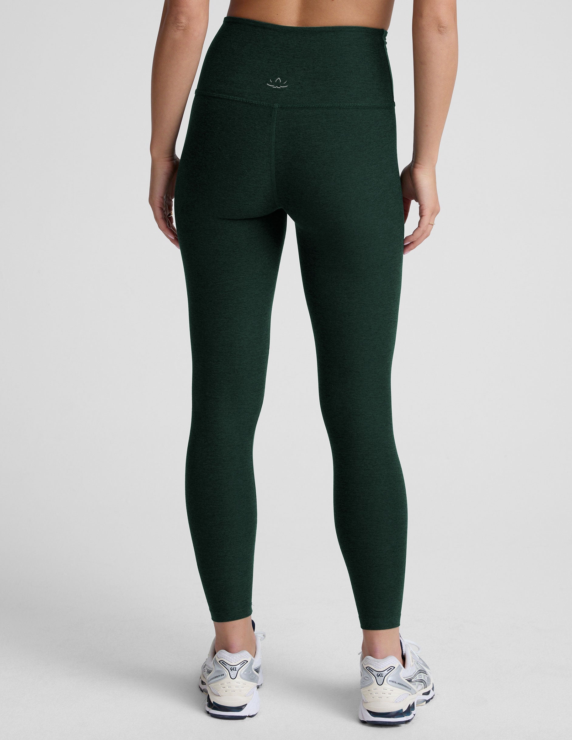 model wearing green high-waisted midi length leggings on a light background.