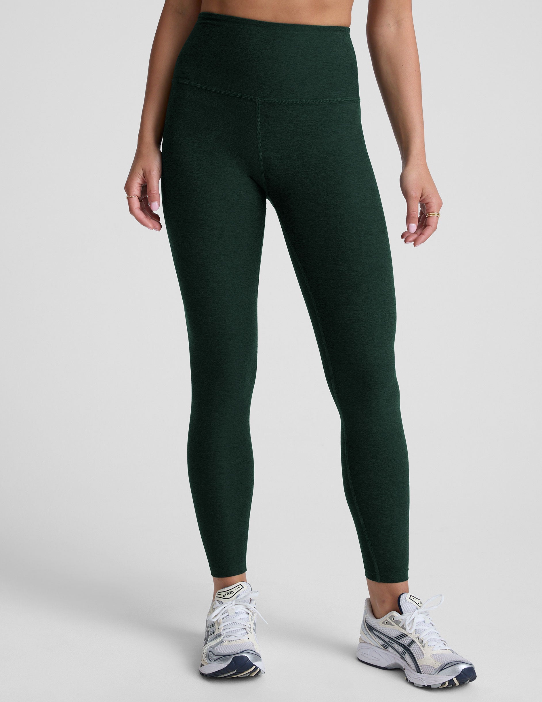 model wearing green high-waisted midi length leggings on a light background.