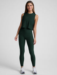 model wearing a green cropped tank and green high-waisted midi length leggings on a light background.