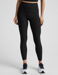 model wearing black high-waisted midi leggings on a white background.