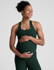 model wearing a green maternity racerback tank and green maternity midi length leggings on a plain background.