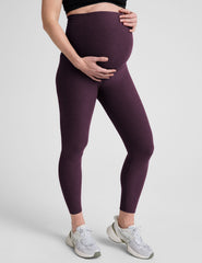 model wearing a purple maternity racerback tank and purple maternity midi length leggings on a plain background.