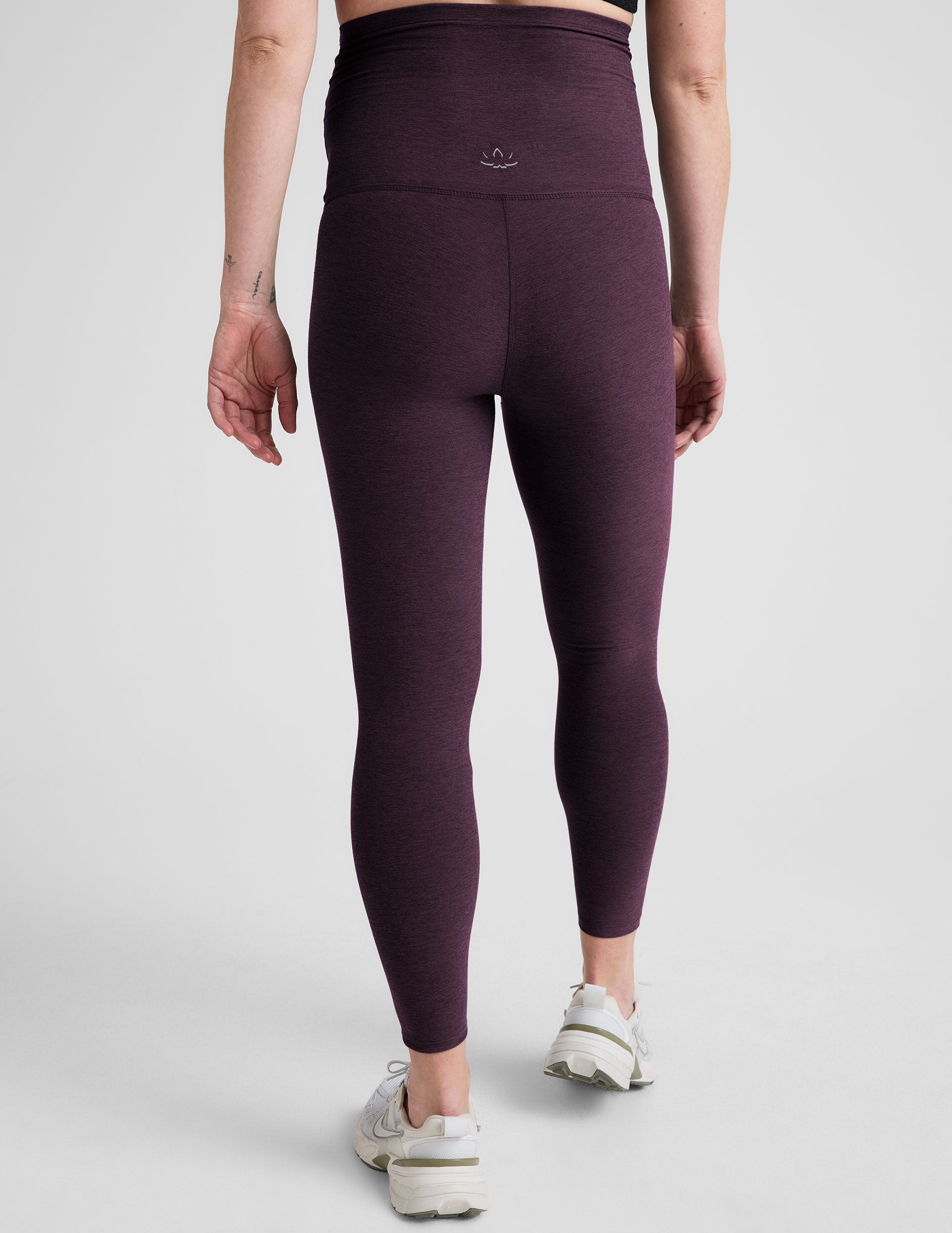 model wearing a purple maternity racerback tank and purple maternity midi length leggings on a plain background.