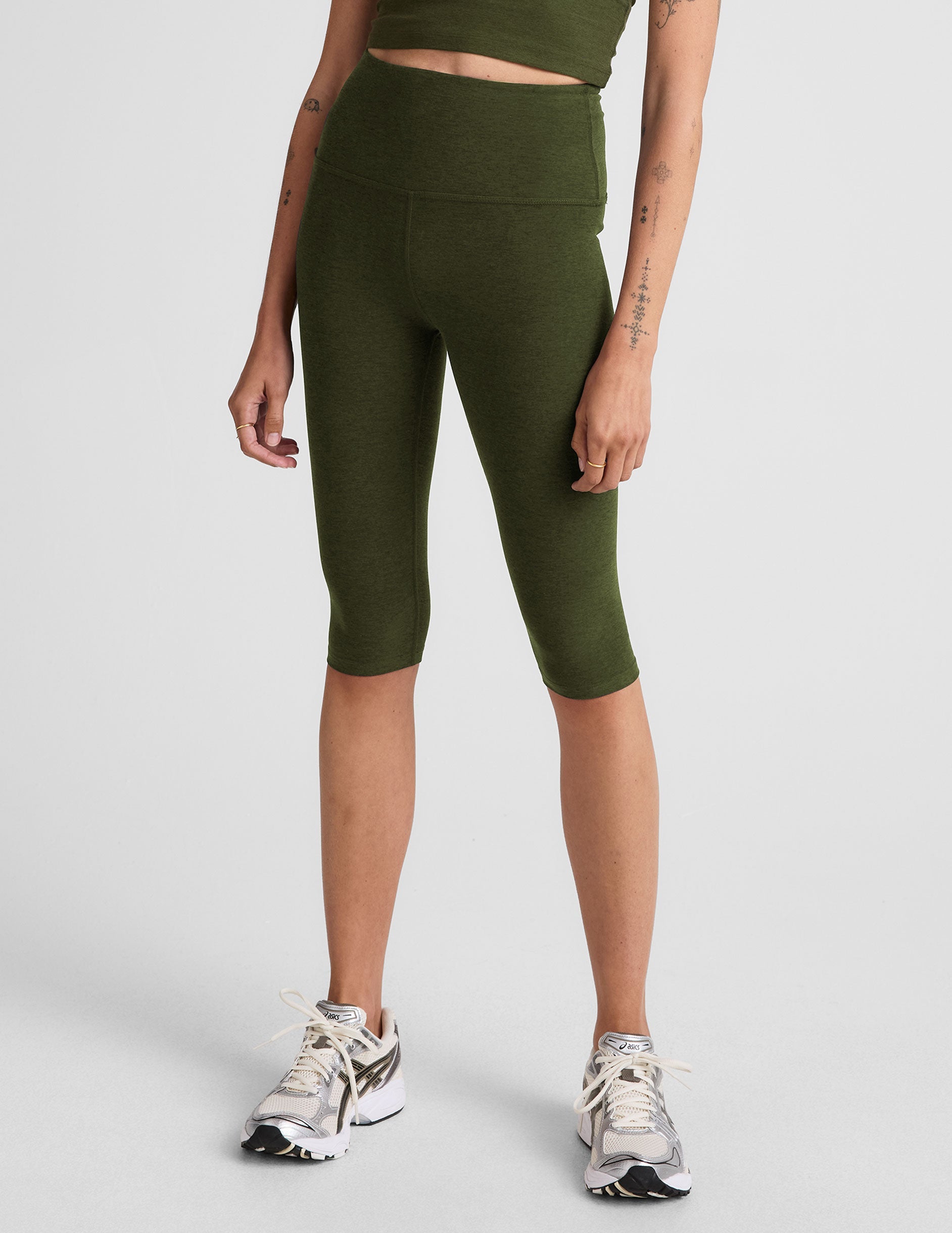 model is wearing green high-waisted pedal pusher length leggings.
