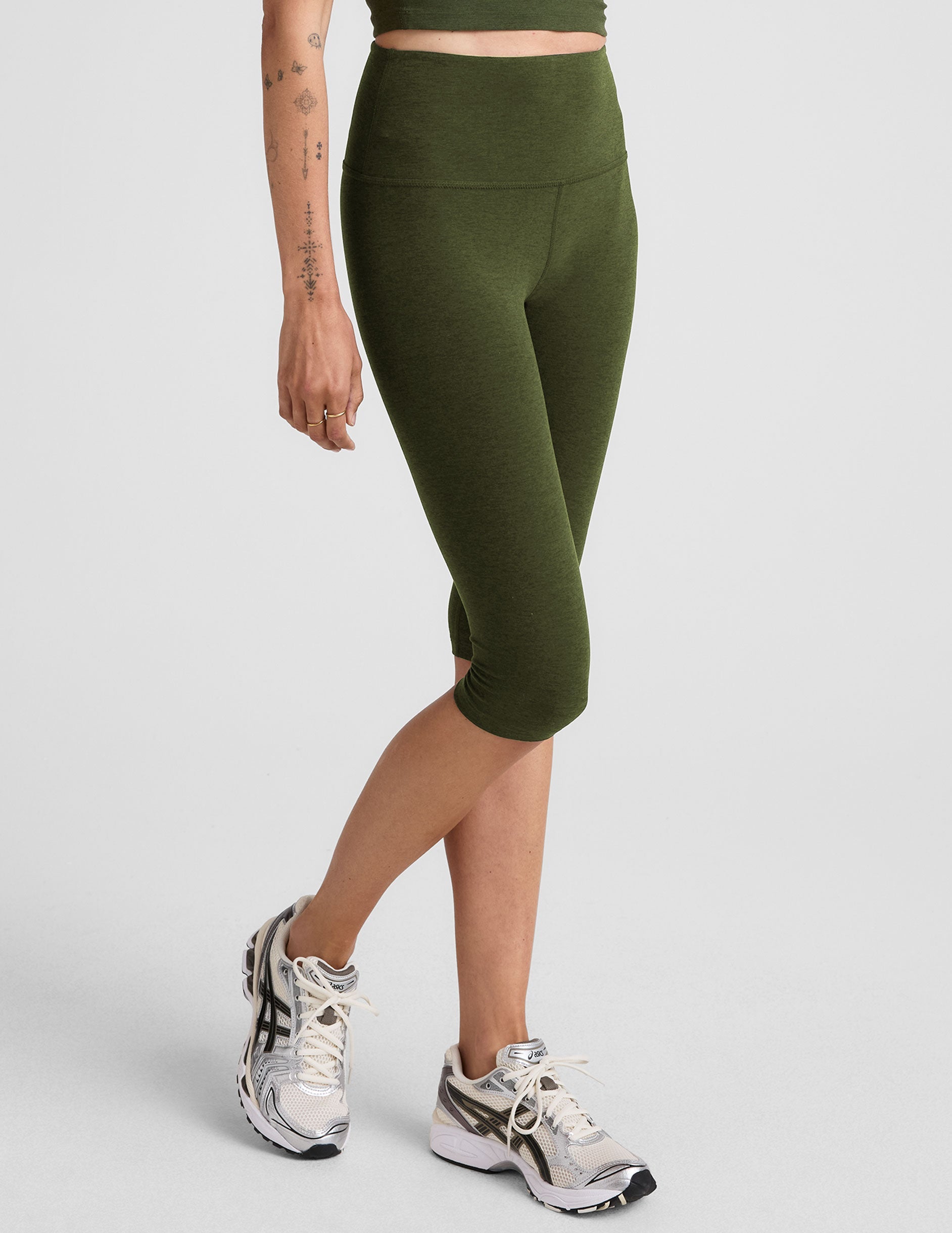 model is wearing green high-waisted pedal pusher length leggings.