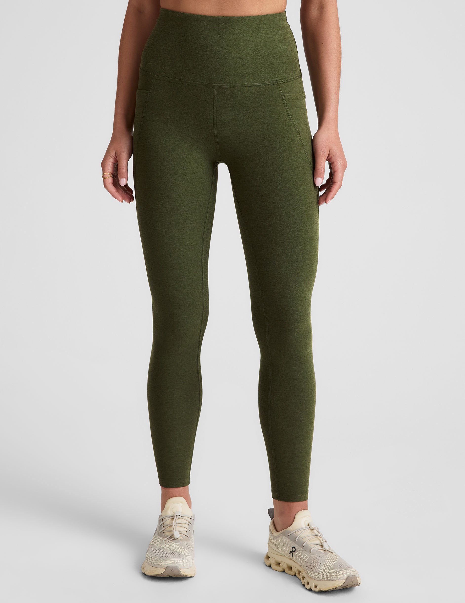 green high-waisted midi length leggings with side pockets on a plain background.