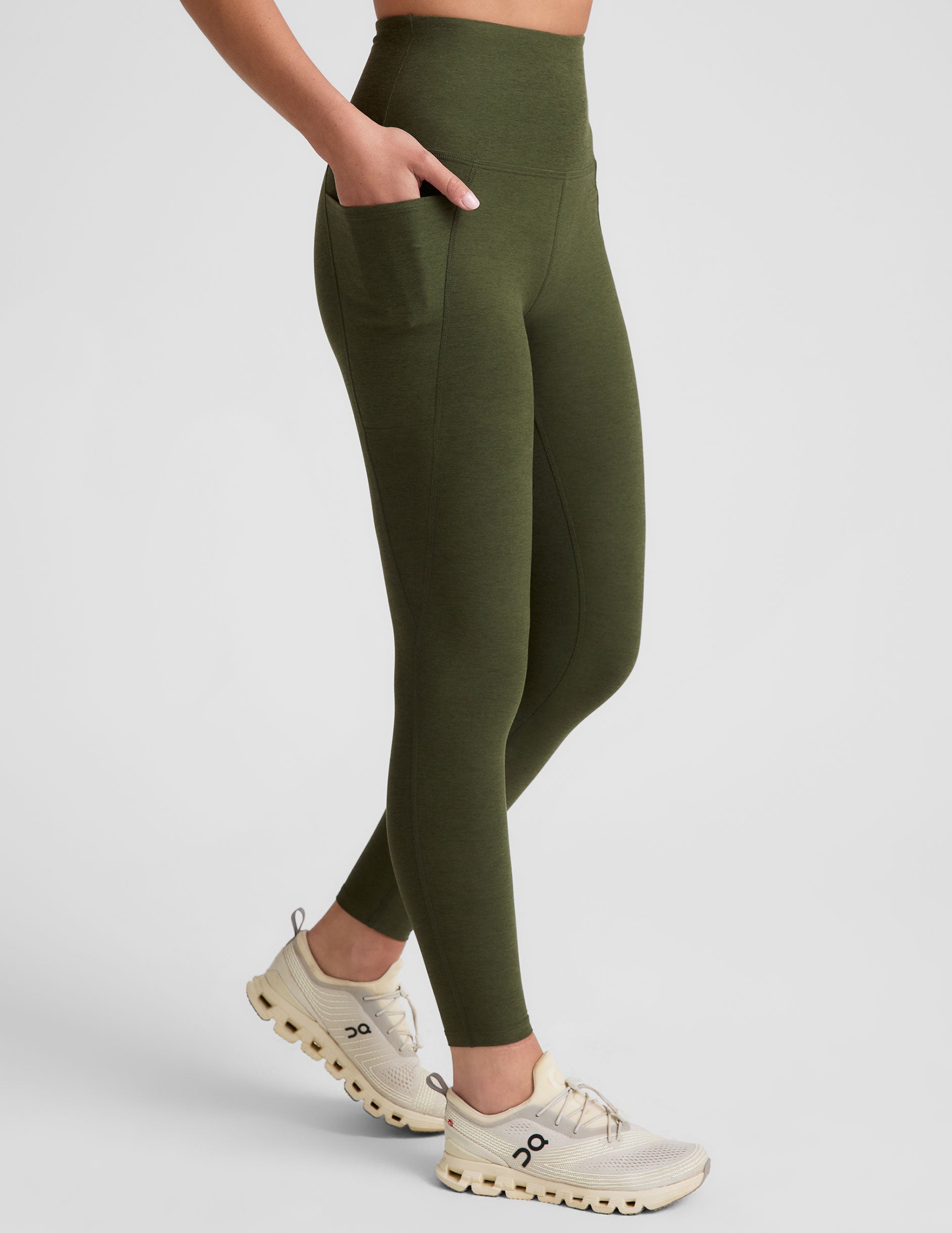 green high-waisted midi length leggings with side pockets on a plain background.