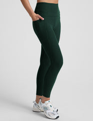 model is wearing green high-waisted midi length leggings with pockets on a plain background.