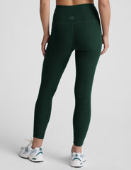model is wearing green high-waisted midi length leggings with pockets on a plain background.