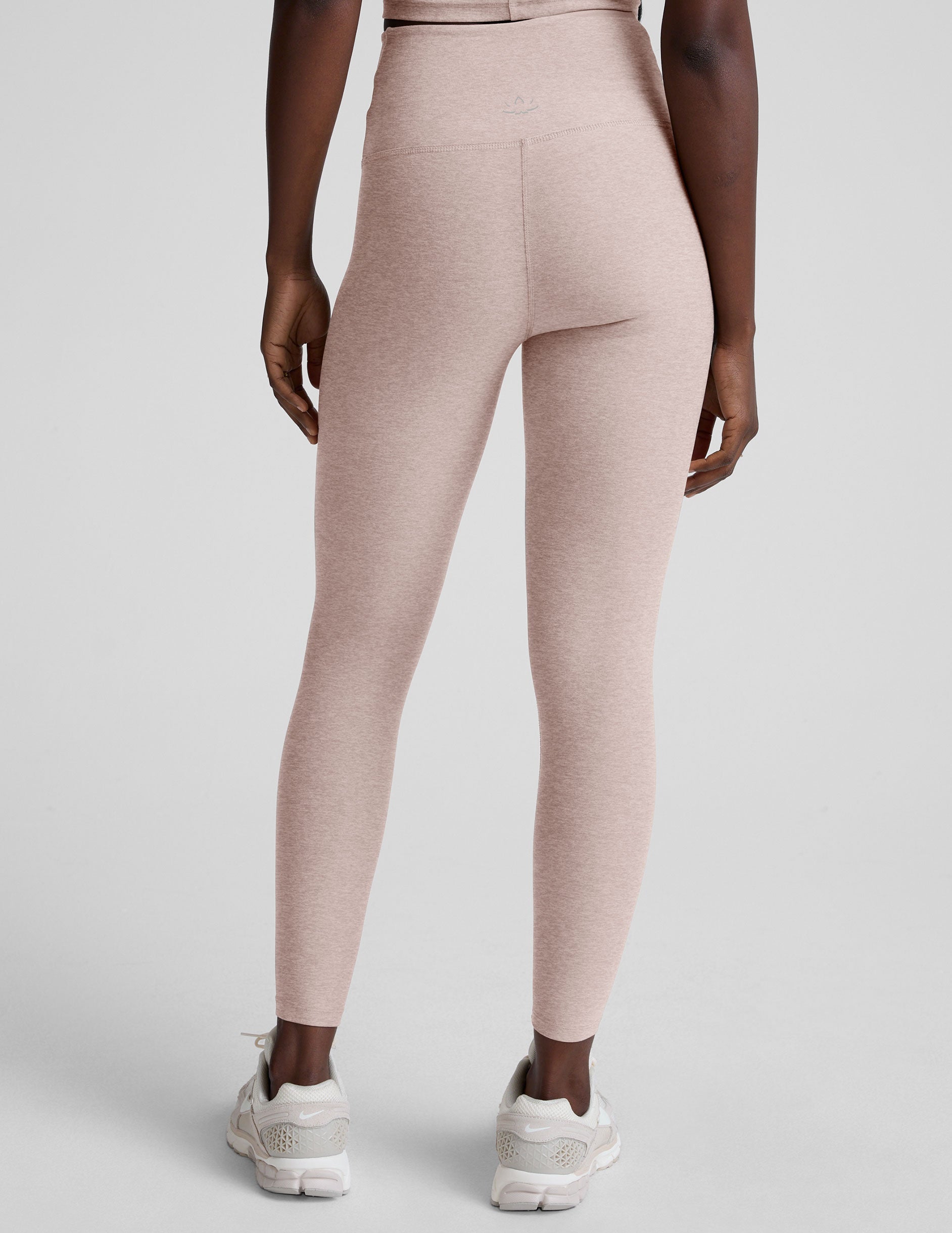 model wearing pink high-waisted leggings with a front crossover detail on a plain background.