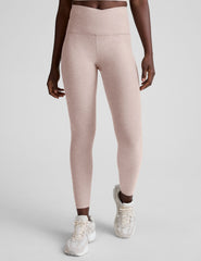 model wearing pink high-waisted leggings with a front crossover detail on a plain background.