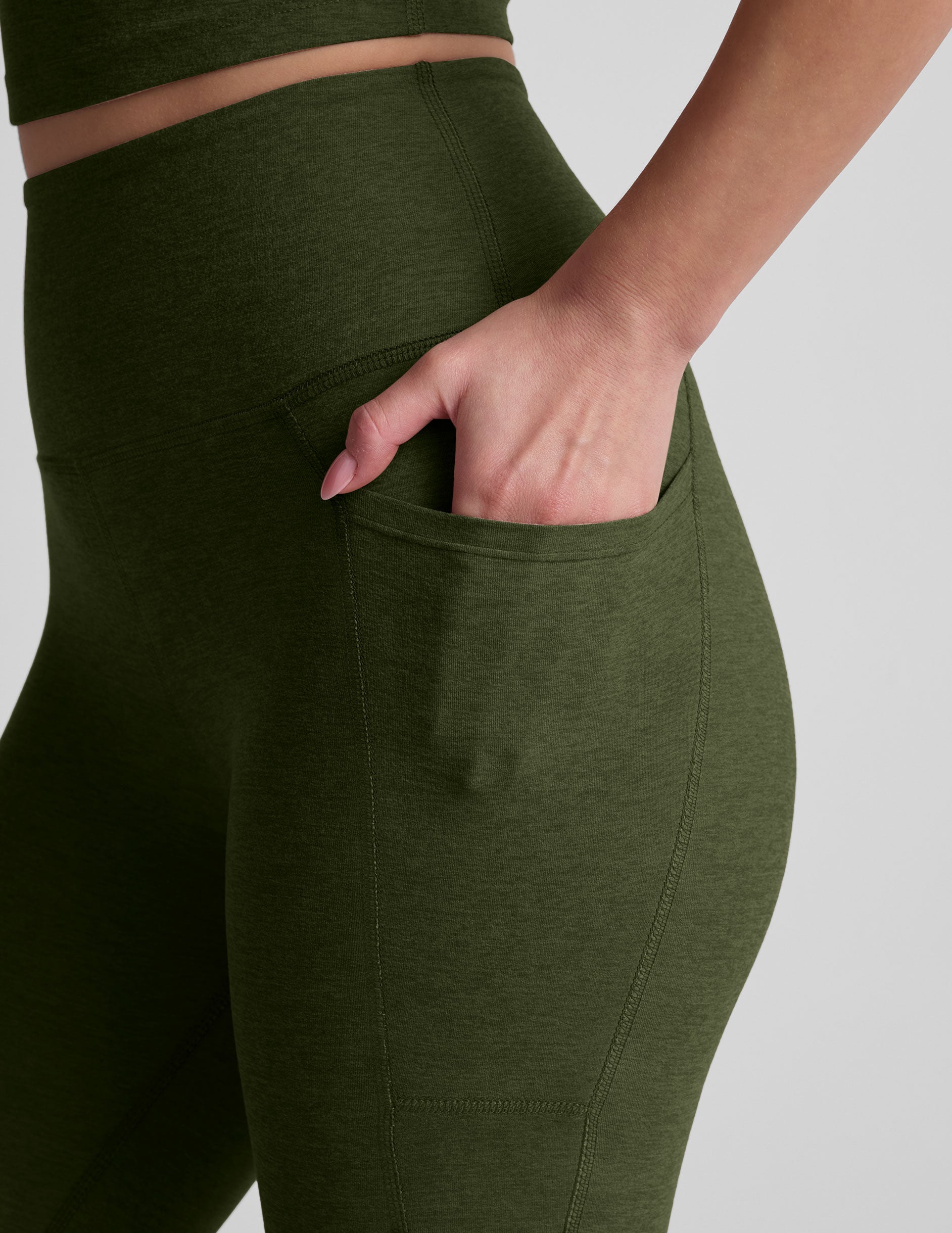 model is wearing green high-waisted capri length leggings with pockets.