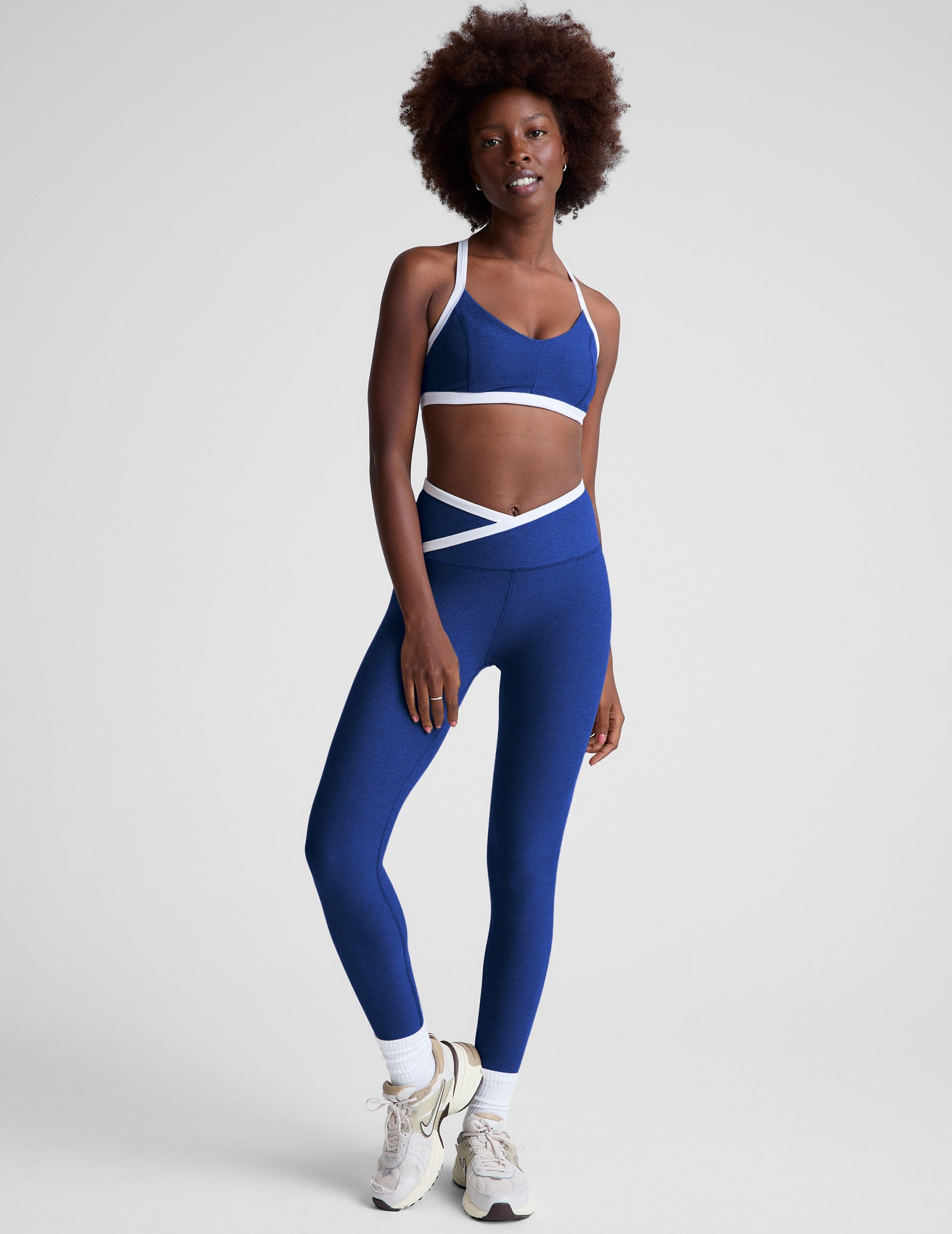 blue high-waisted midi length legging with a crossover detail on the front waistband with white contrast binding along waistline.
