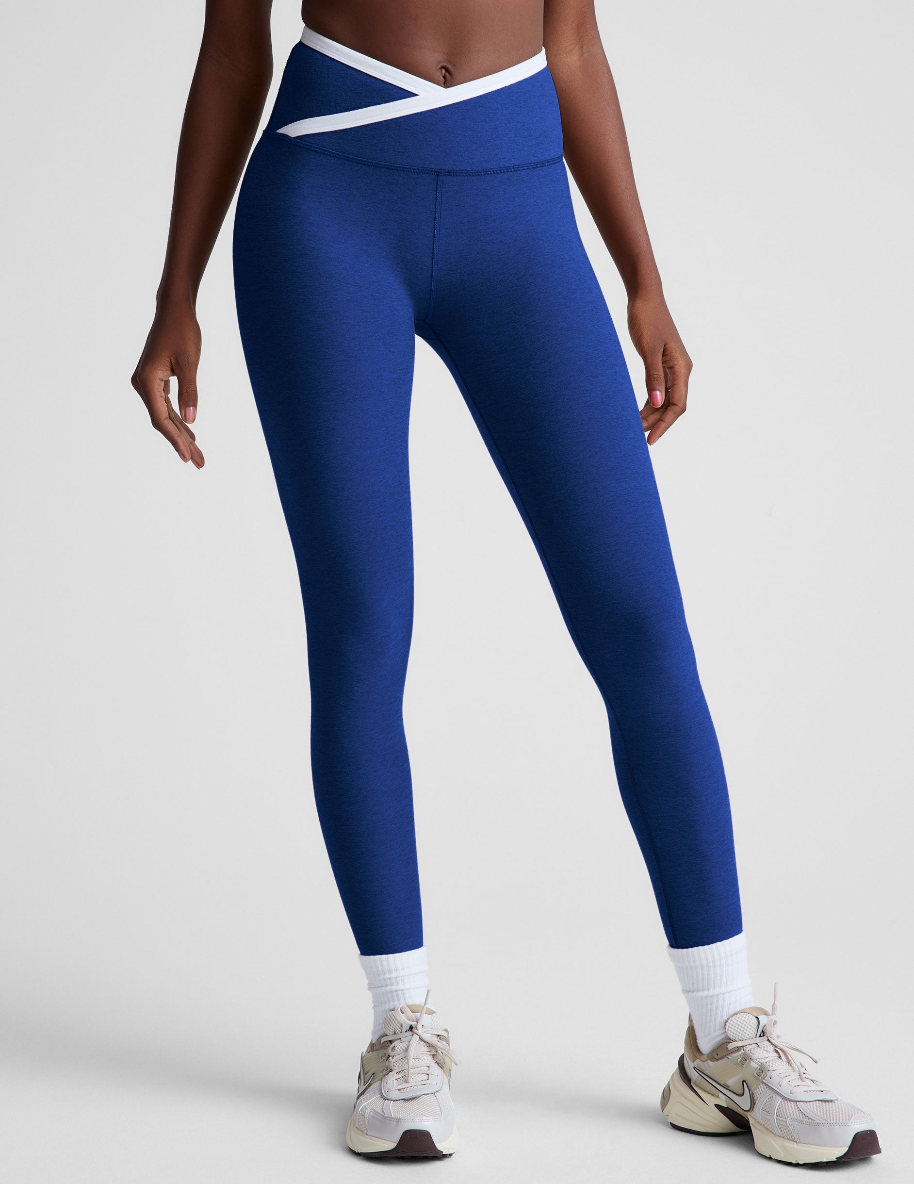 blue high-waisted midi length legging with a crossover detail on the front waistband with white contrast binding along waistline.