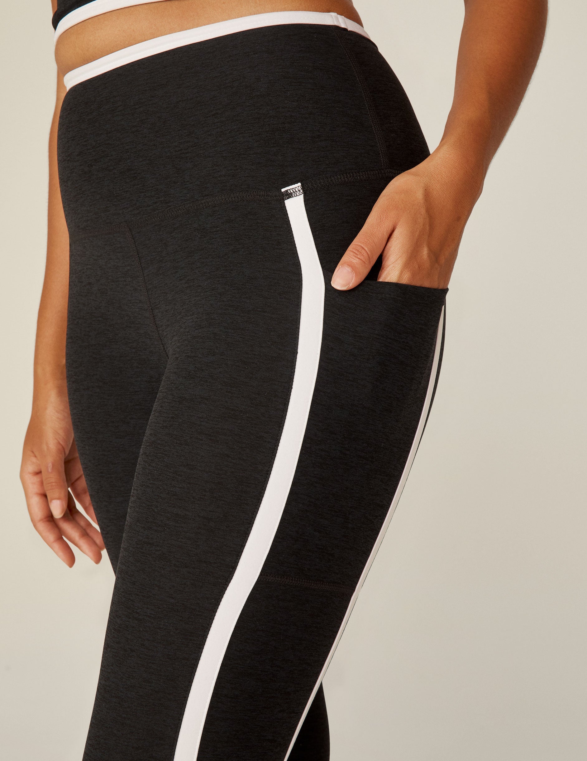 black pocket high-waisted midi legging with white lining around waistband and down the sides.