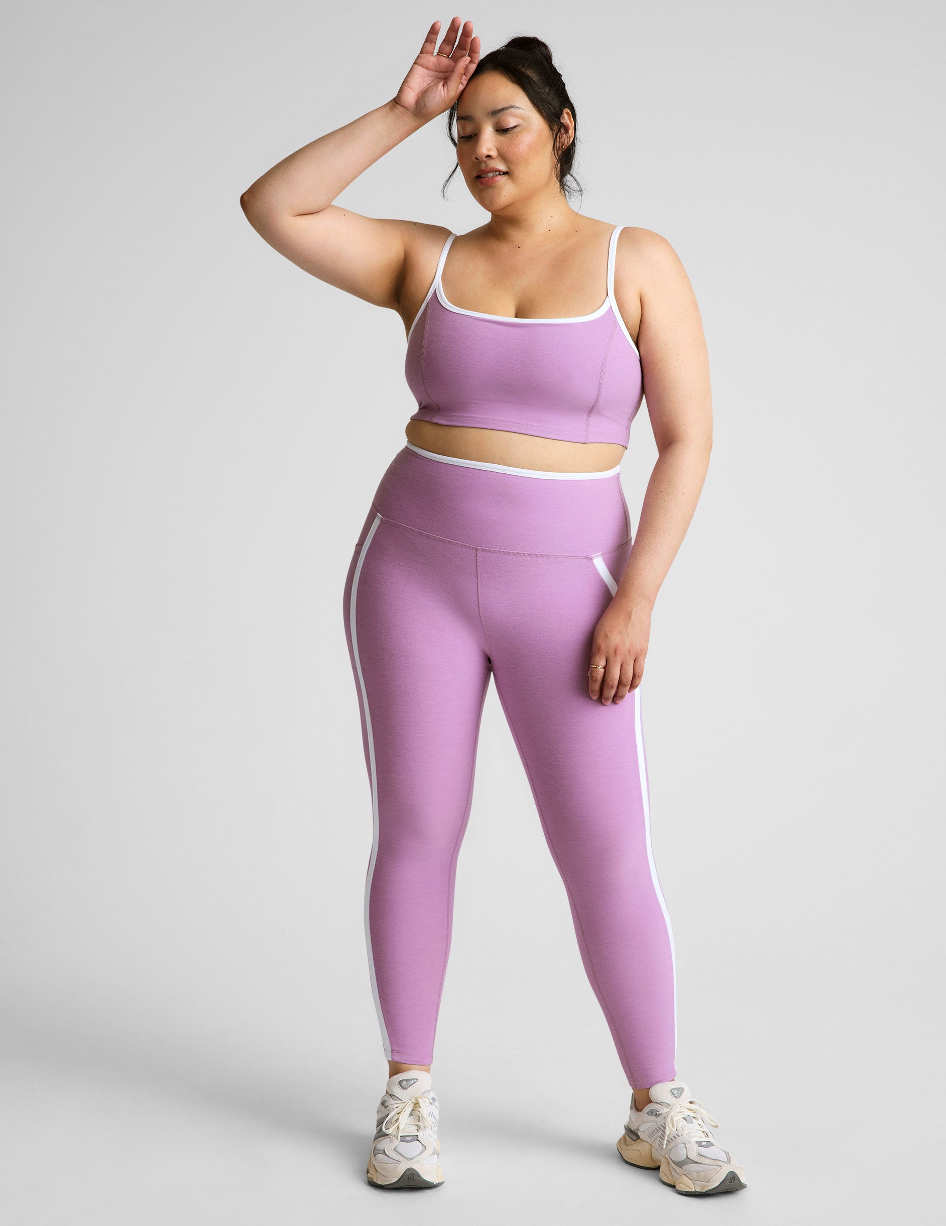 purple high-waisted midi length legging with pockets and white piping.