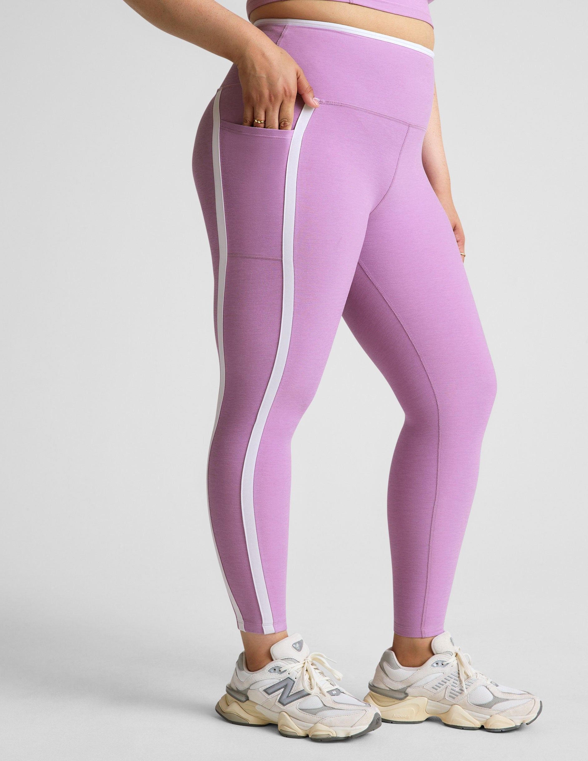 purple high-waisted midi length legging with pockets and white piping.