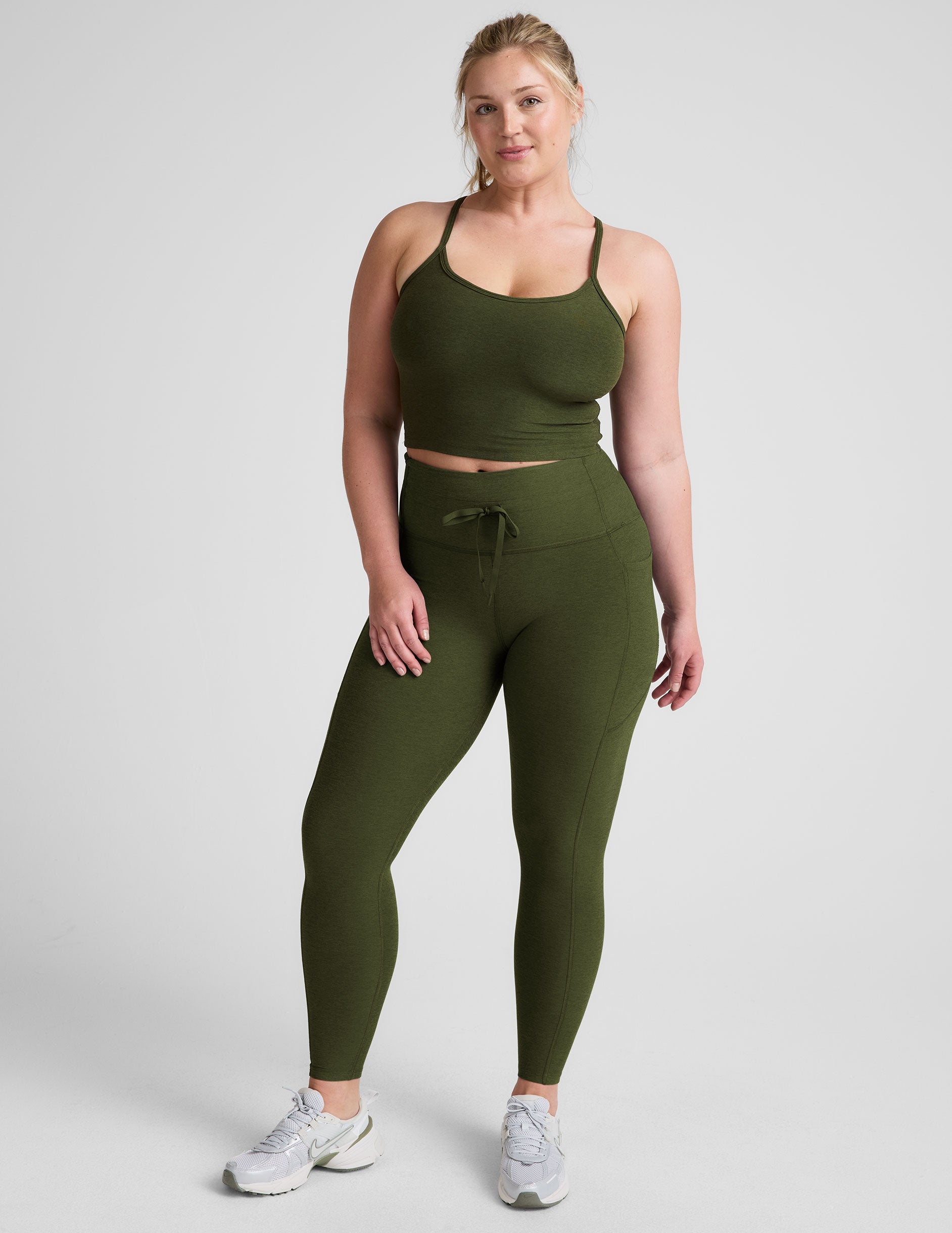 green high-waisted midi length leggings with pockets and a drawstring at waistband.