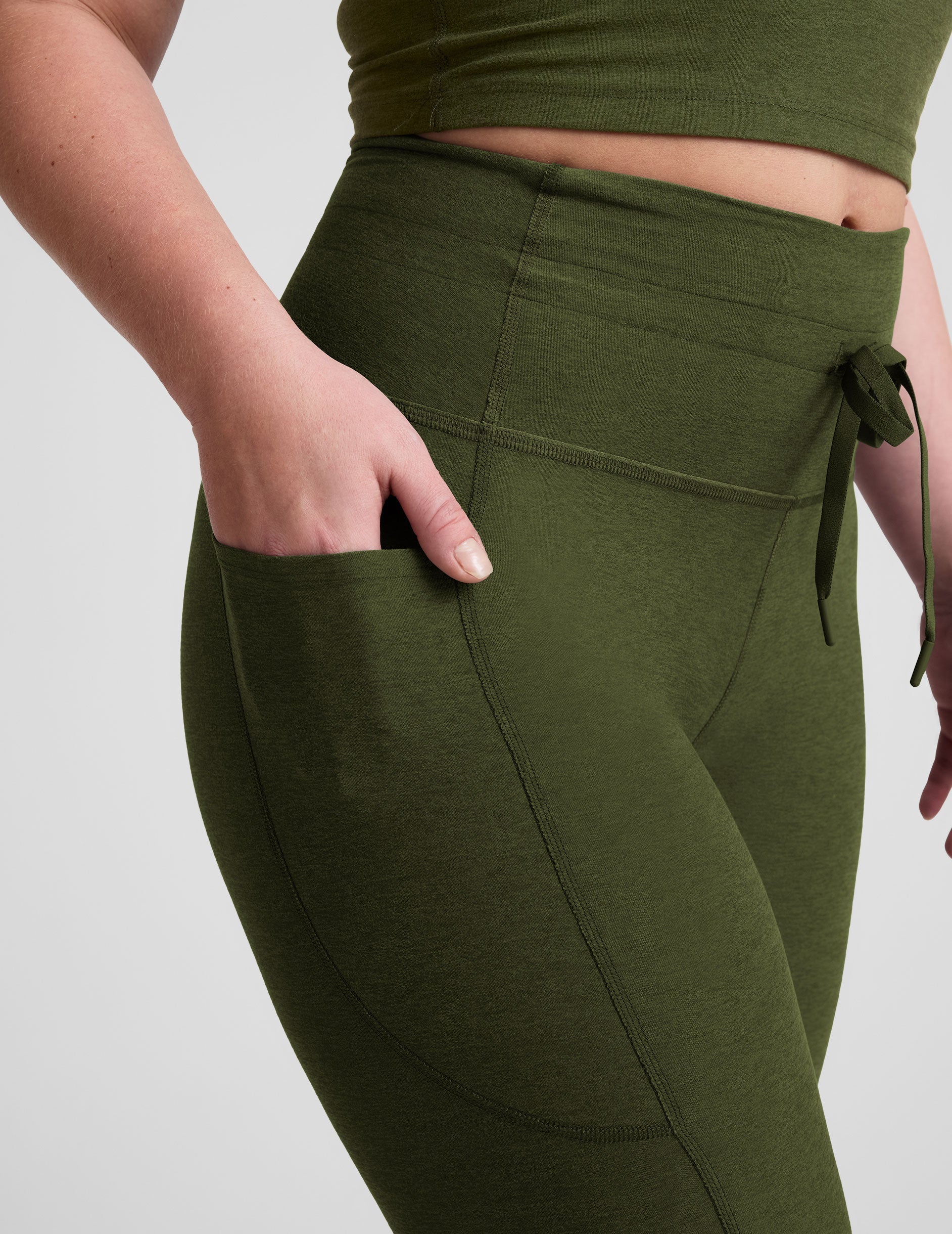 green high-waisted midi length leggings with pockets and a drawstring at waistband.