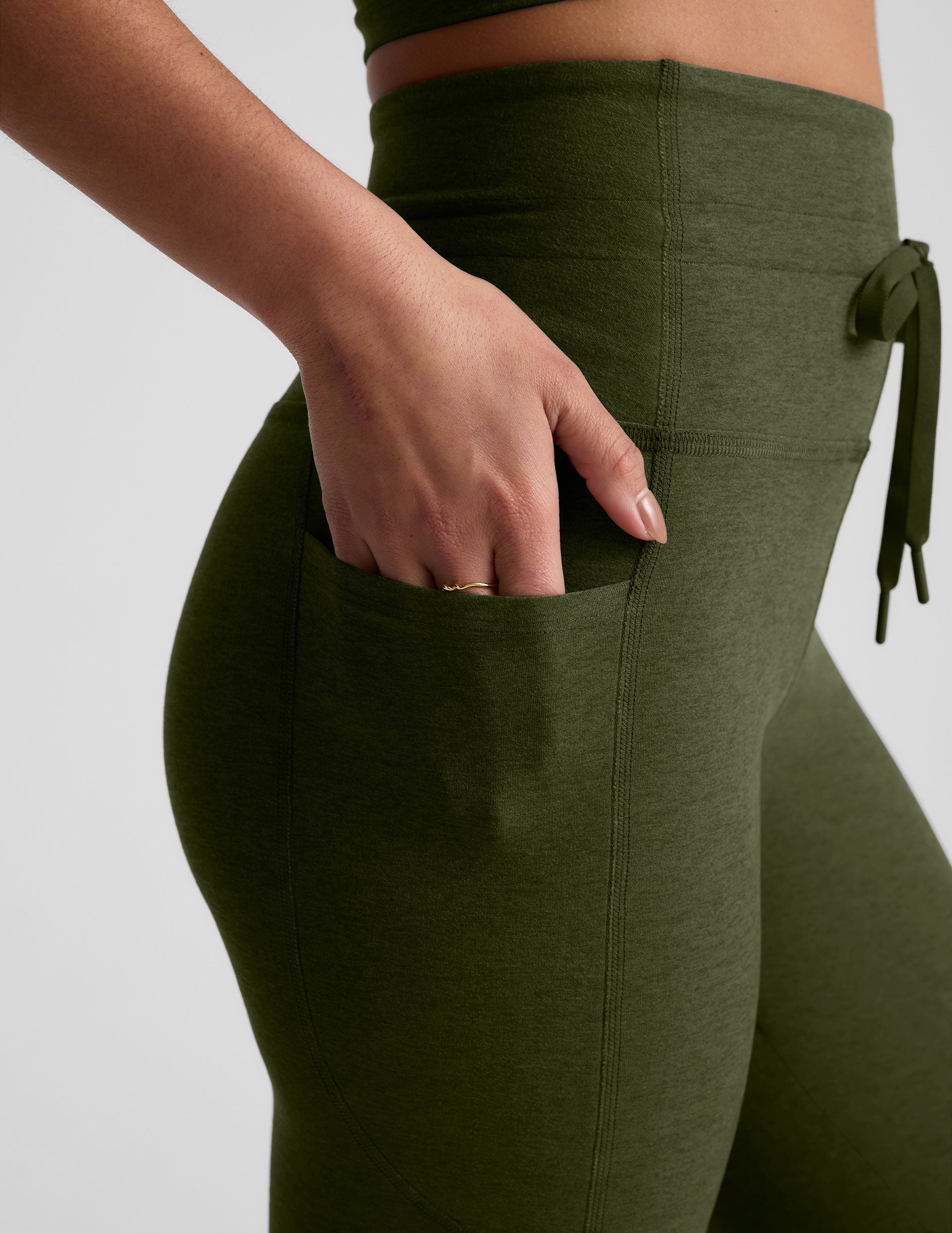 green high-waisted midi length leggings with pockets and a drawstring at waistband.